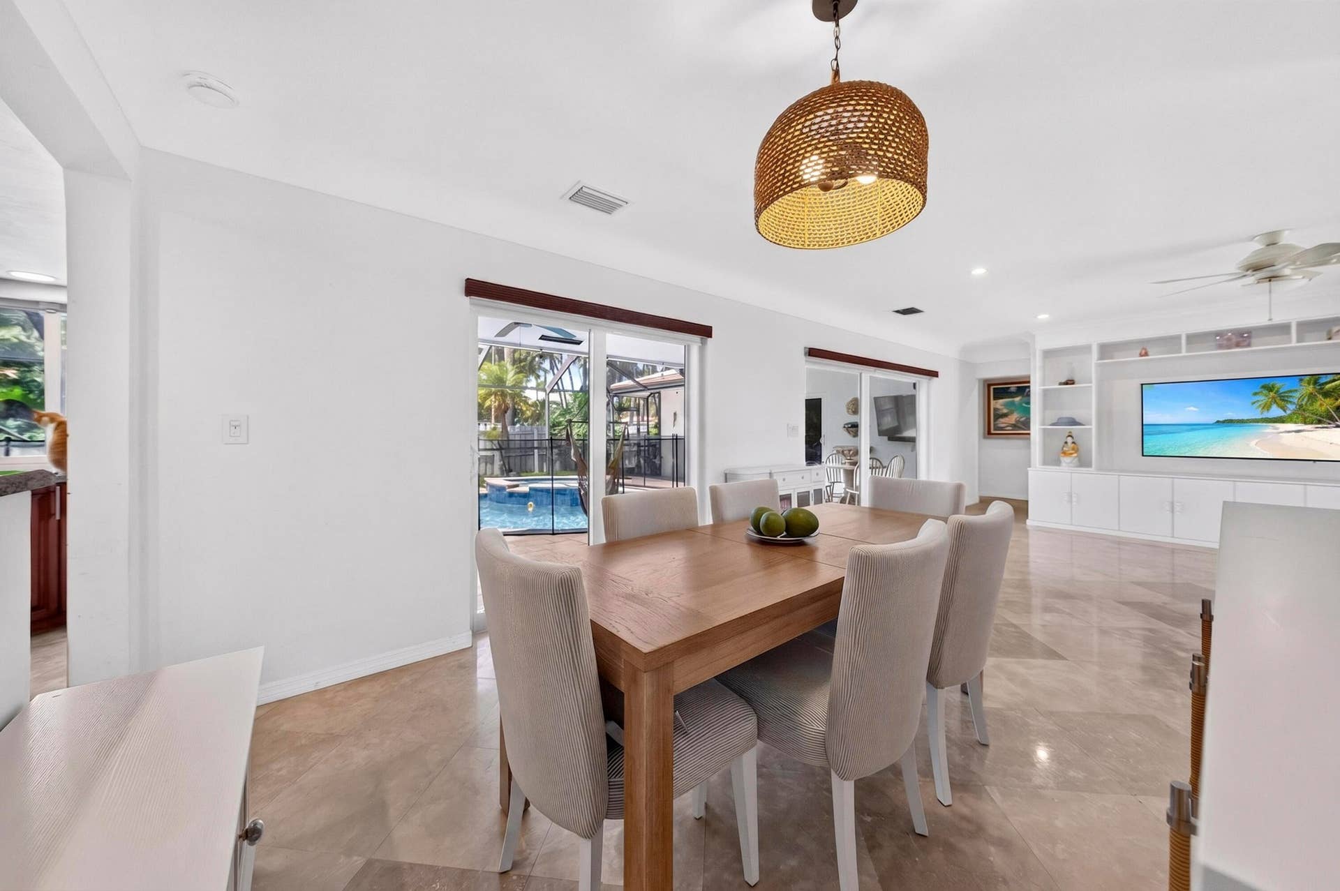 Dining area featuring large format tile flooring, a woven pendant light fixture, and direct access to an outdoor pool area through sliding glass doors