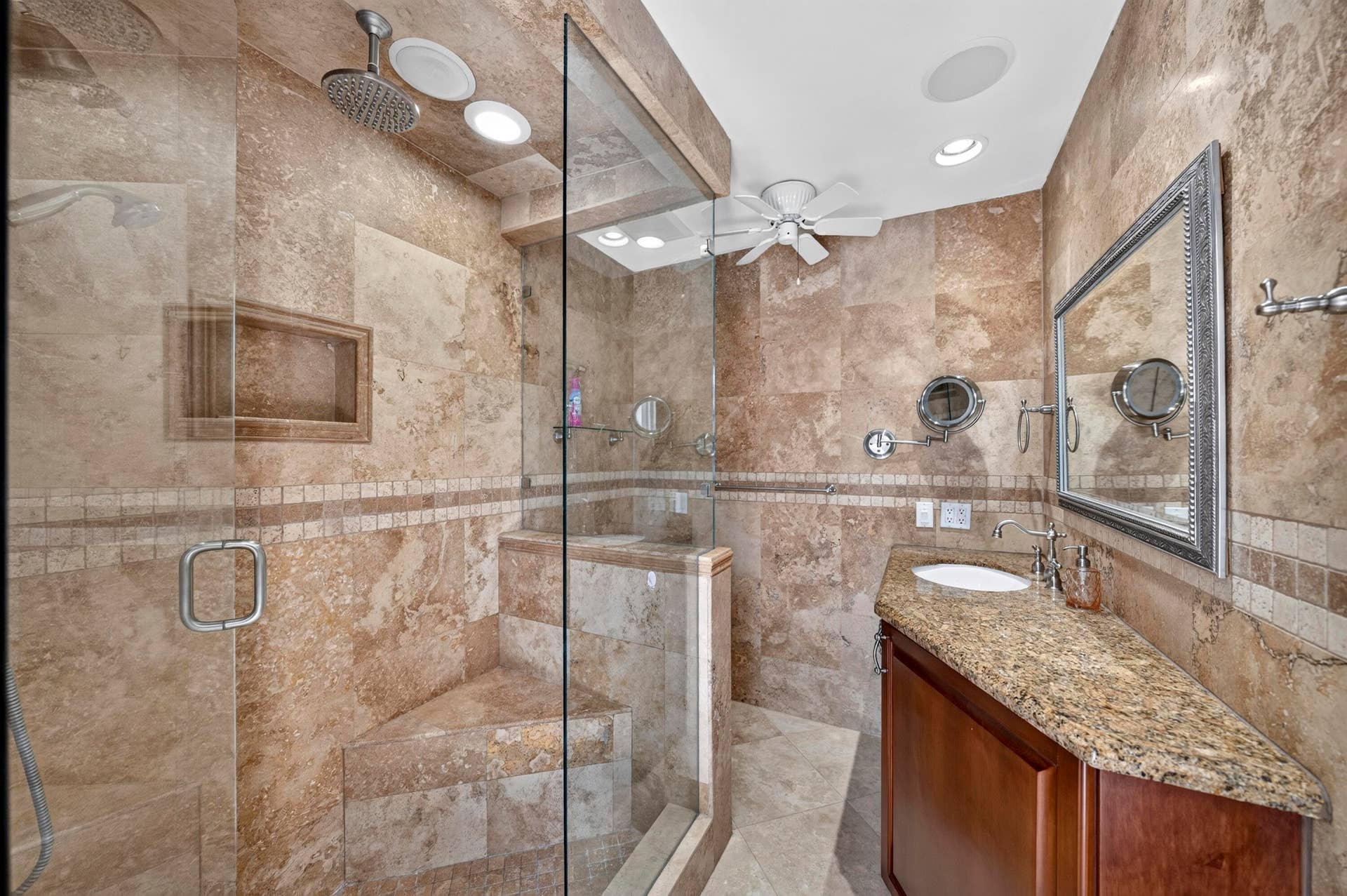 Tiled bathroom featuring a glass-enclosed steam shower with a built-in bench and recessed shelf