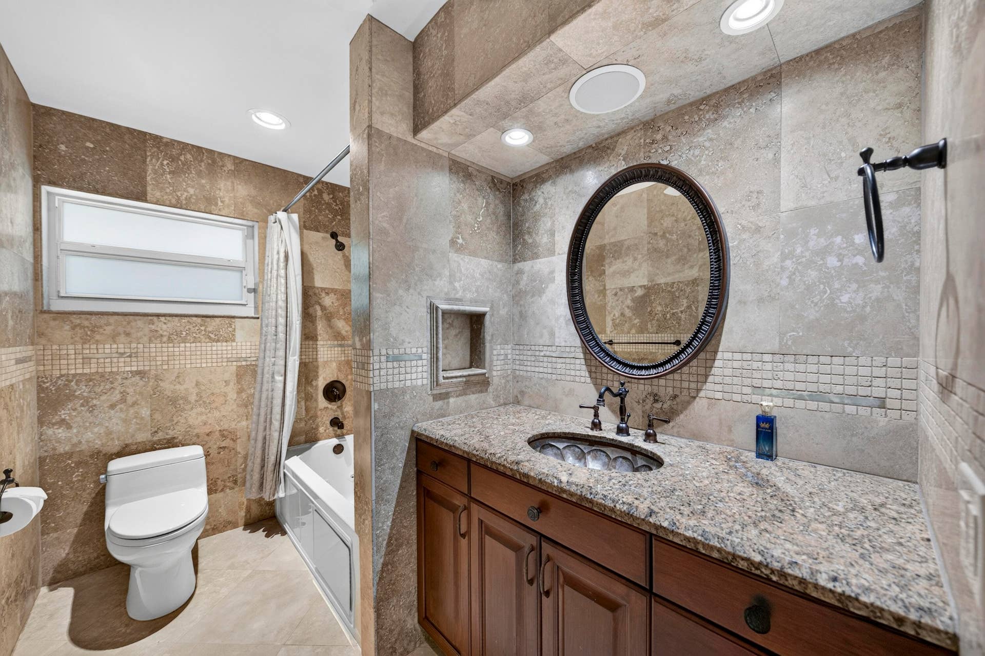 2nd full bathroom featuring a granite countertop vanity with a decorative vessel sink, an oval framed mirror, recessed lighting, and tiled walls with decorative mosaic accents