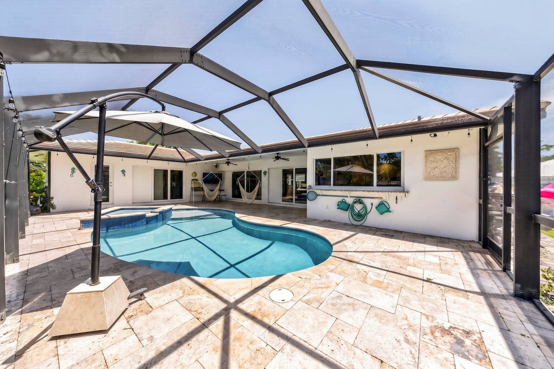 Screened pool enclosure featuring a freeform swimming pool and integrated spa