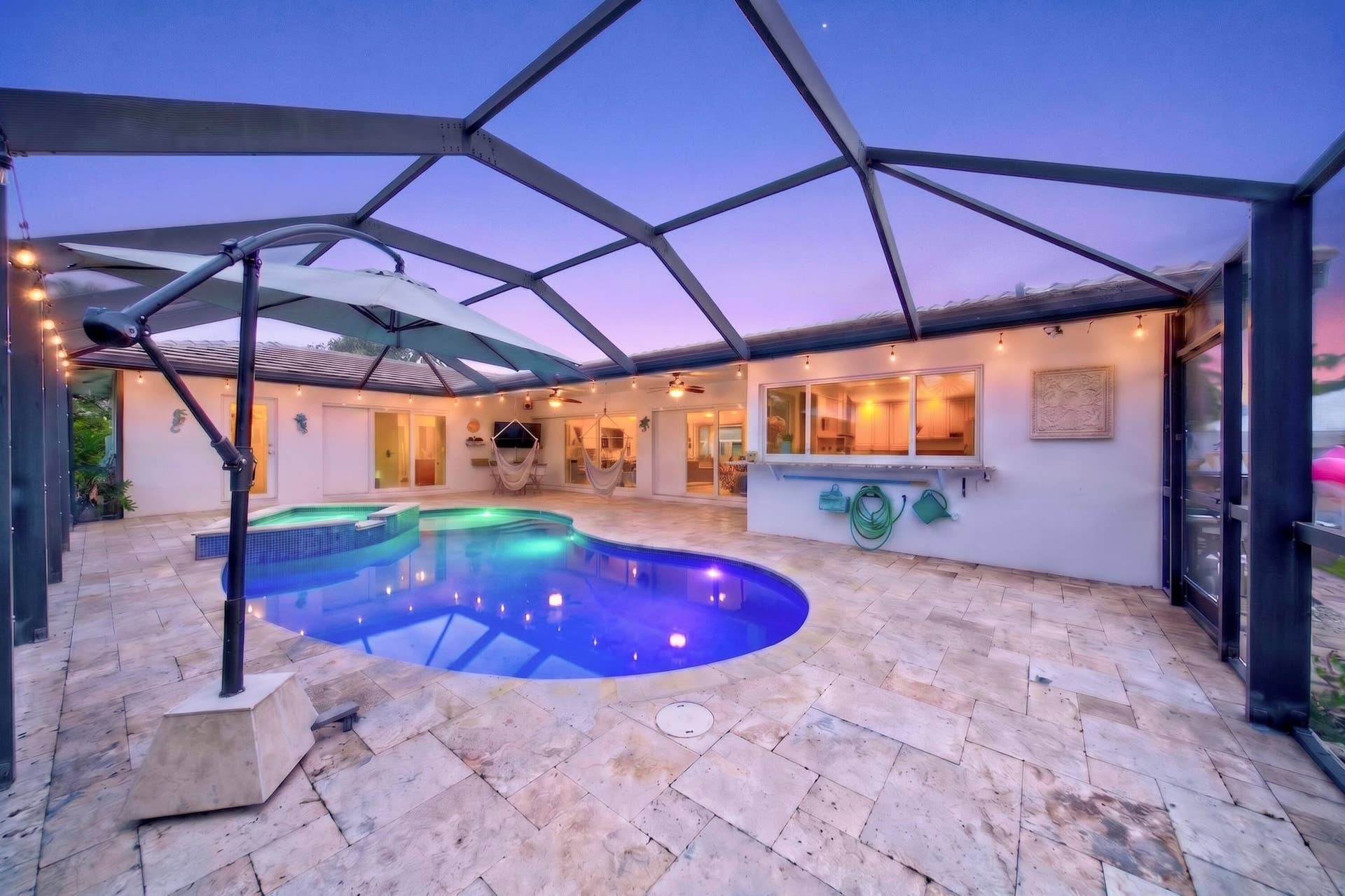 Screened patio featuring a freeform pool, integrated spa, and expansive stone tile decking