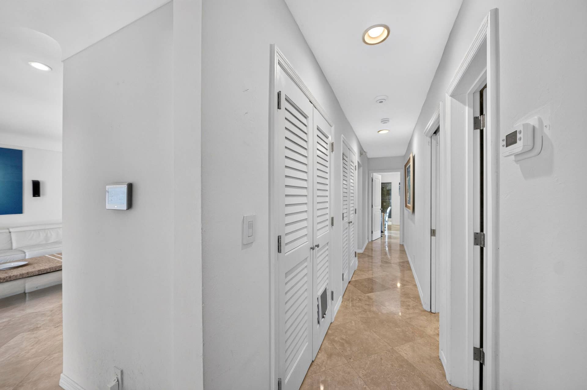 Hallway featuring recessed lighting, louvered bi-fold doors, multiple doorways, and marble flooring