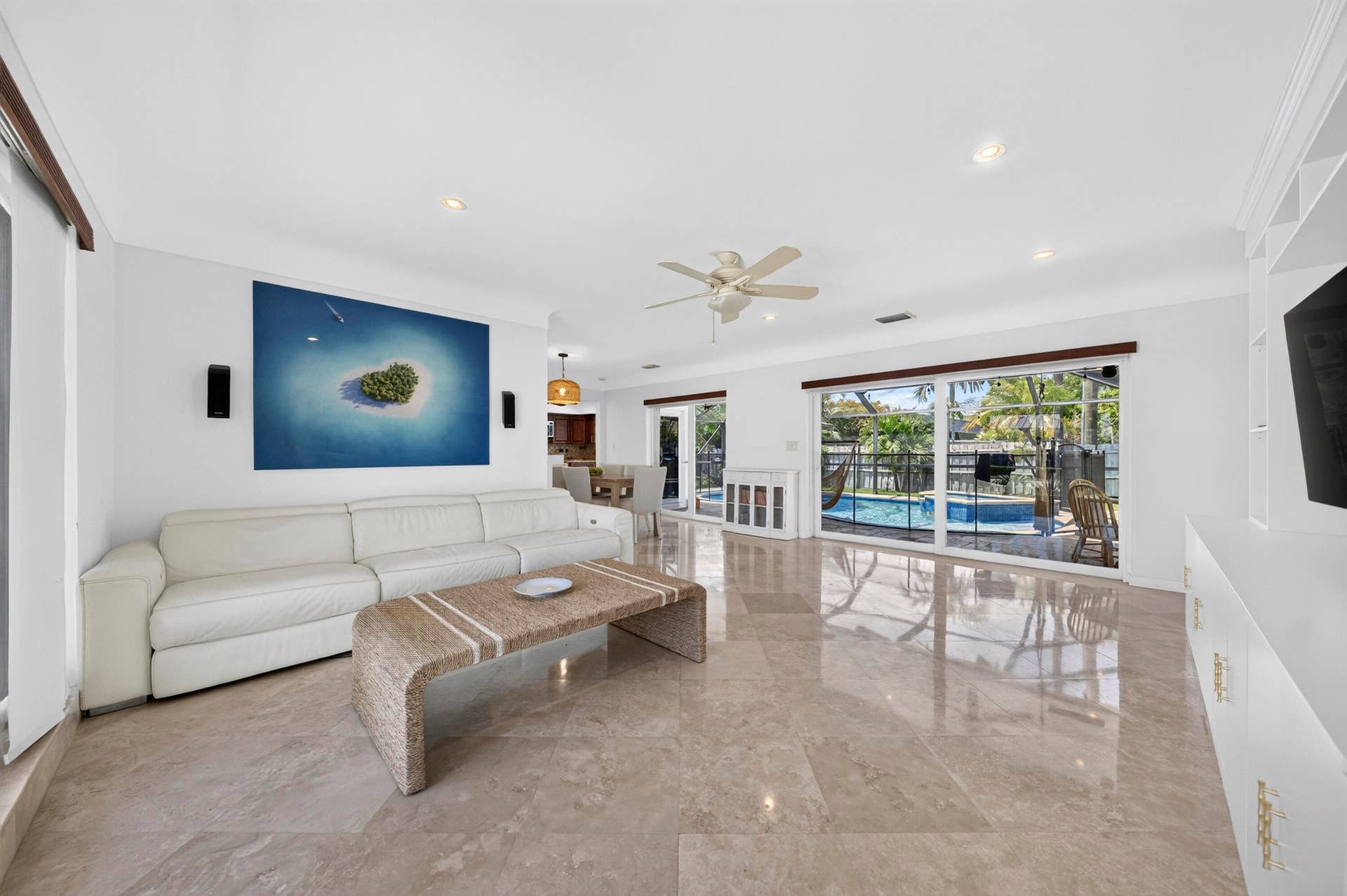 Spacious living area featuring polished Travertine marble flooring, recessed lighting, and a ceiling fan