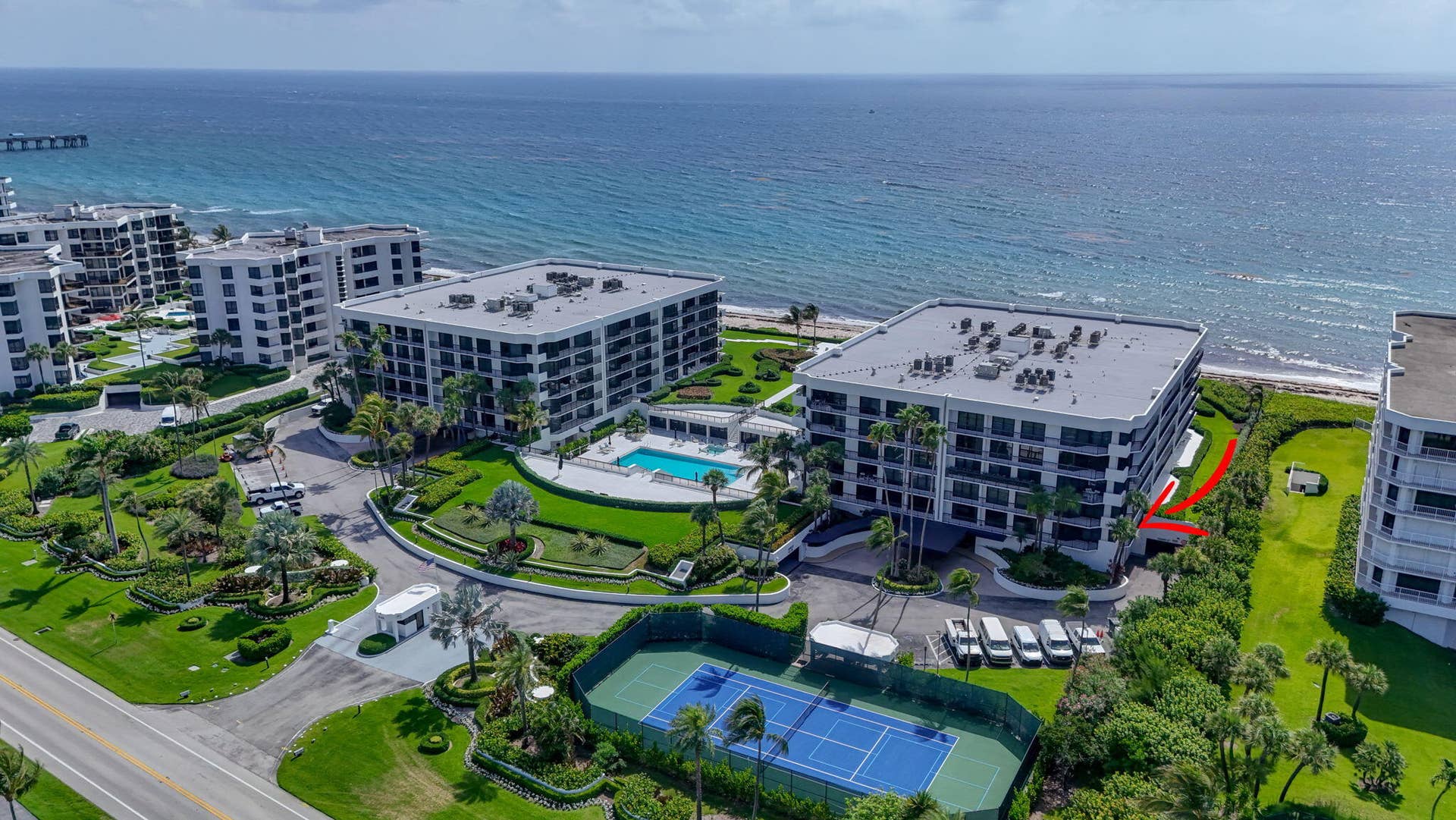 3140 S Ocean Boulevard, #101 S, Palm Beach, FL 33480 Oceanfront condominium building featuring multiple balconies, a ground-level swimming pool with a paved deck, and an adjacent tennis court