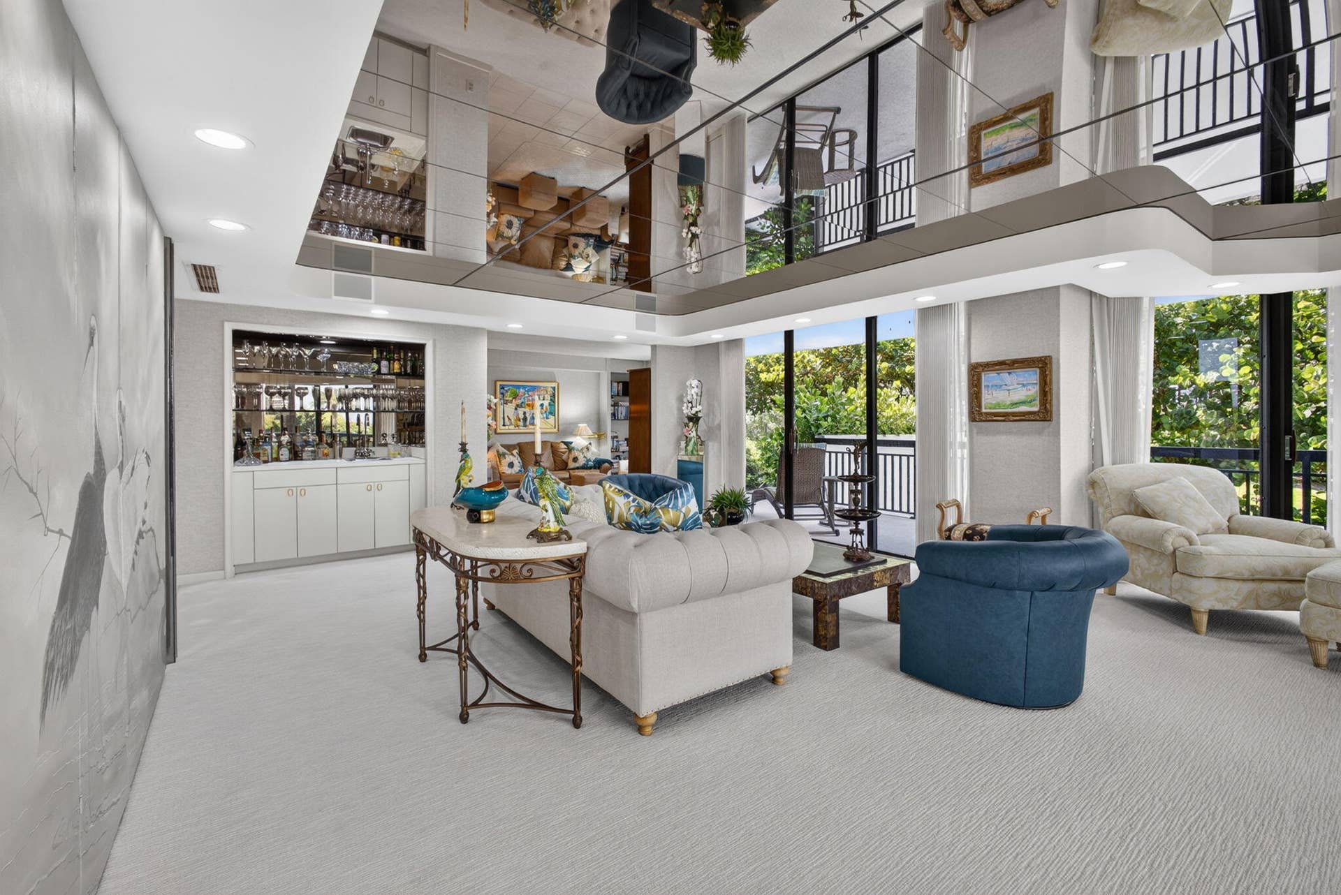 3140 S Ocean Boulevard, #101 S, Palm Beach, FL 33480 Spacious living area featuring a mirrored ceiling, built-in wet bar with cabinetry, full-height windows, and a second-story balcony overlooking the space