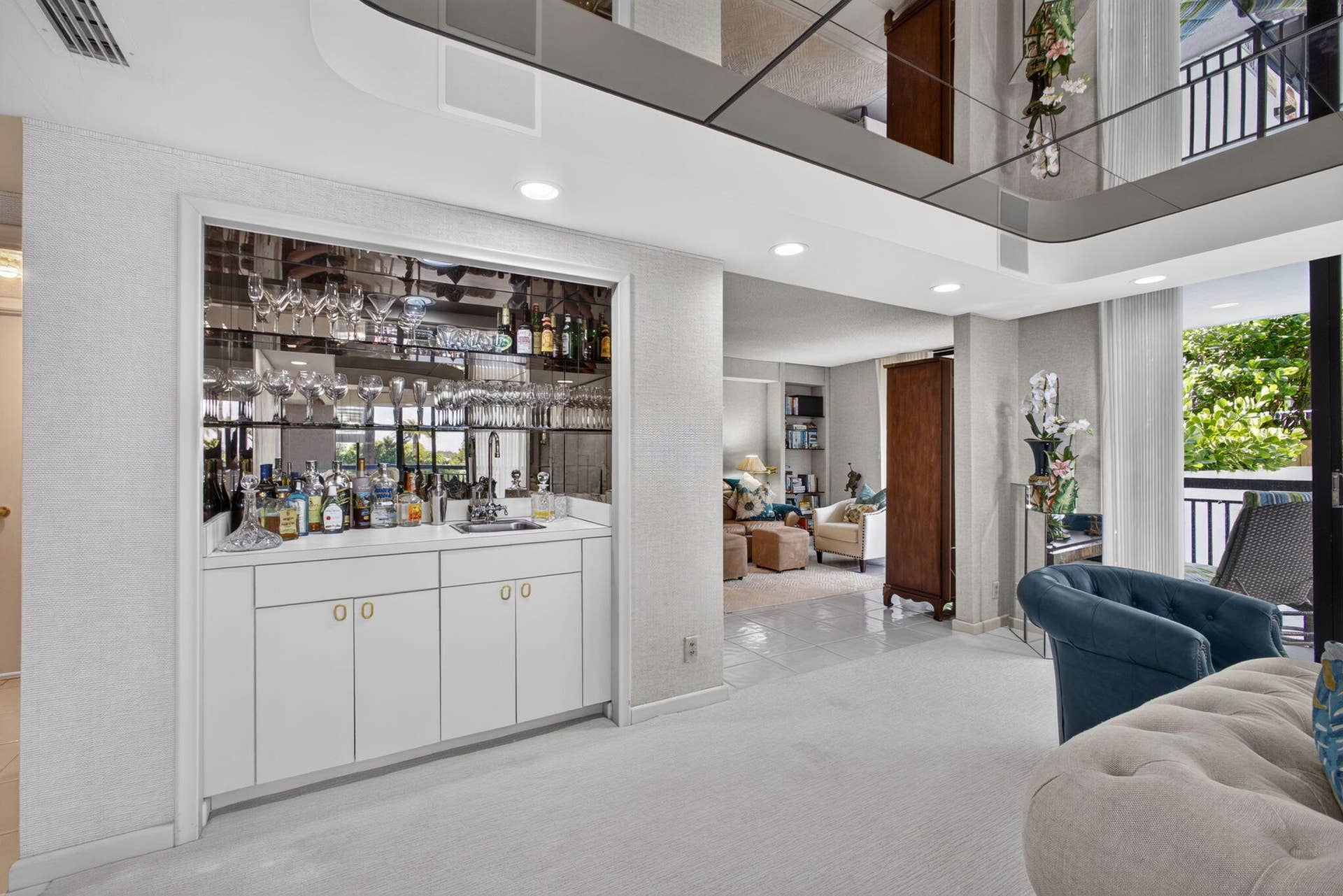 3140 S Ocean Boulevard, #101 S, Palm Beach, FL 33480 Built-in wet bar featuring white cabinetry, a countertop, and a mirrored backsplash with integrated stemware storage