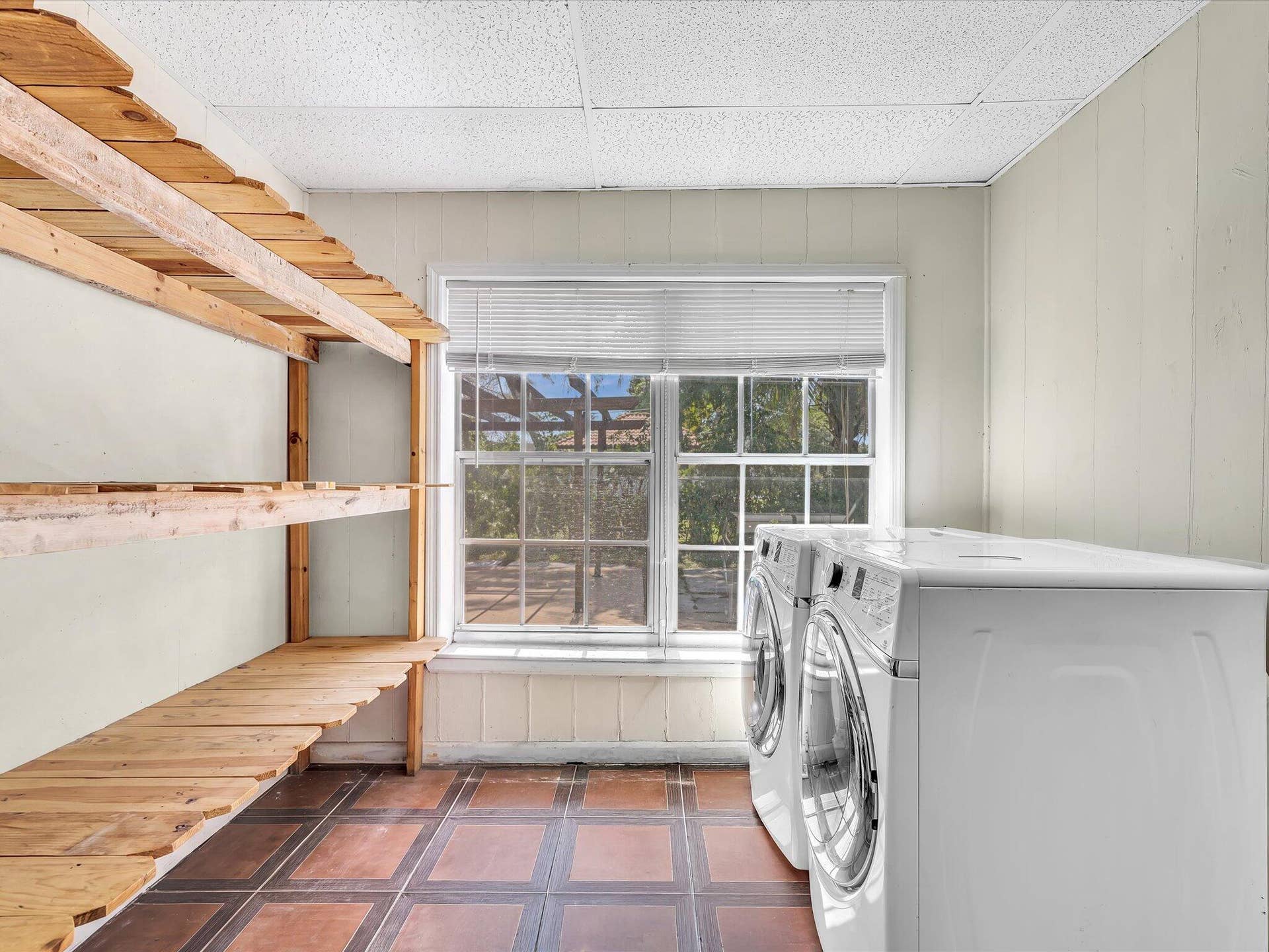 Utility area with extensive wood shelving and terracotta-style floor tiling