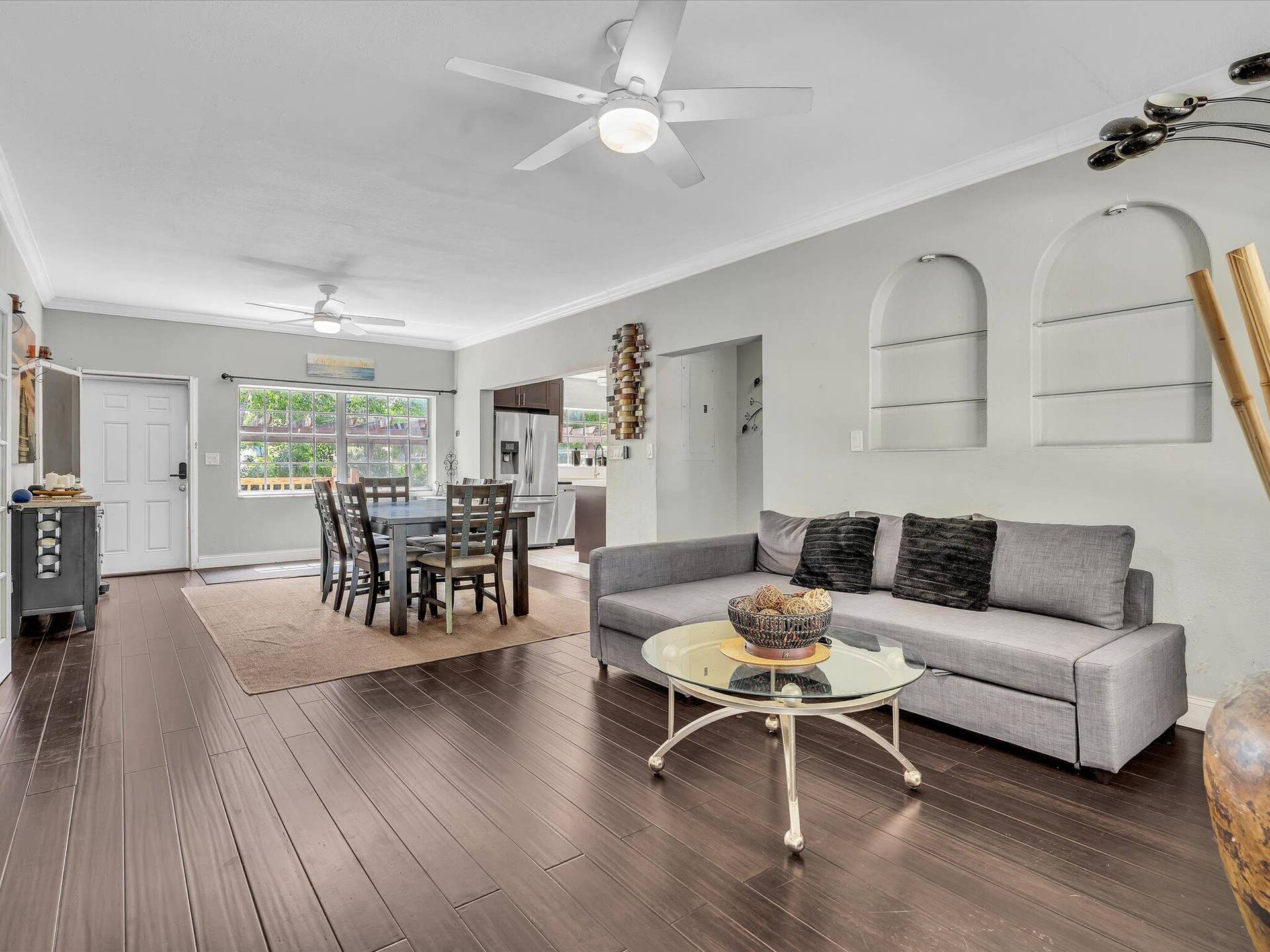 Open-concept living area featuring wood-finish flooring, recessed wall niches, and ceiling fans