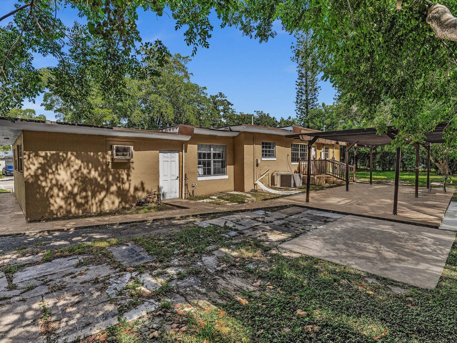 Exterior featuring stucco siding, multiple windows with grilles, and a white entry door