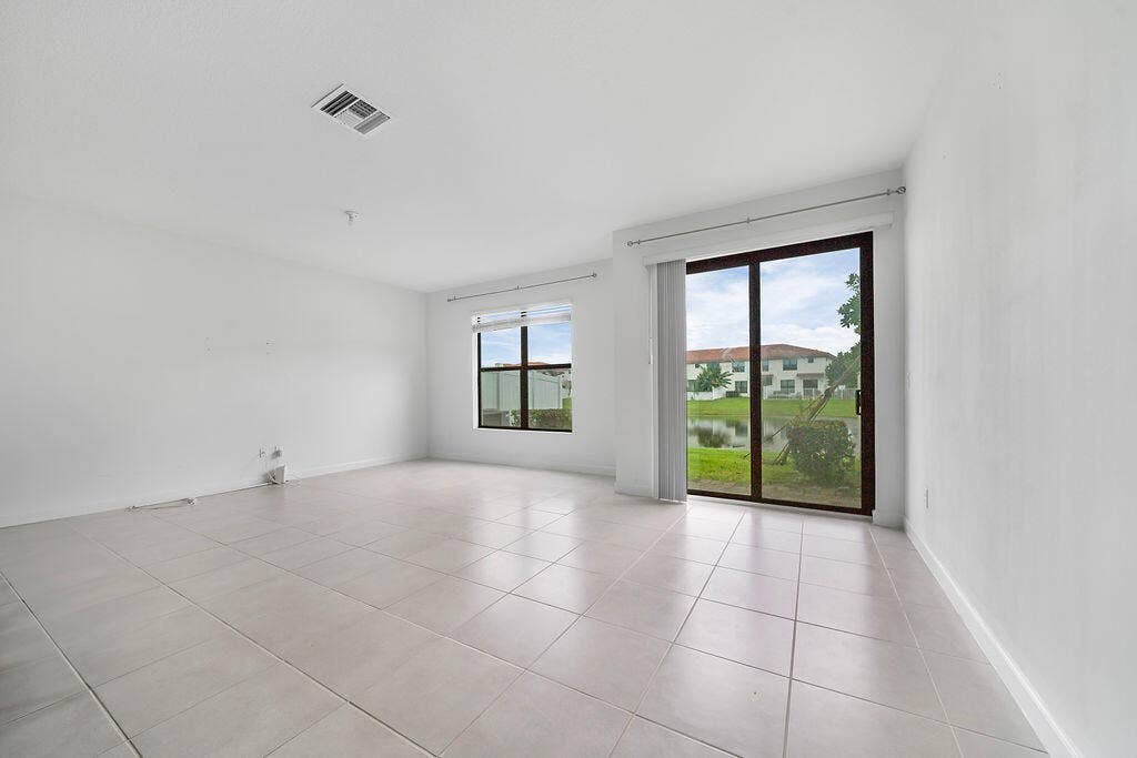 Spacious room featuring tile flooring, a large sliding glass door, and an additional window