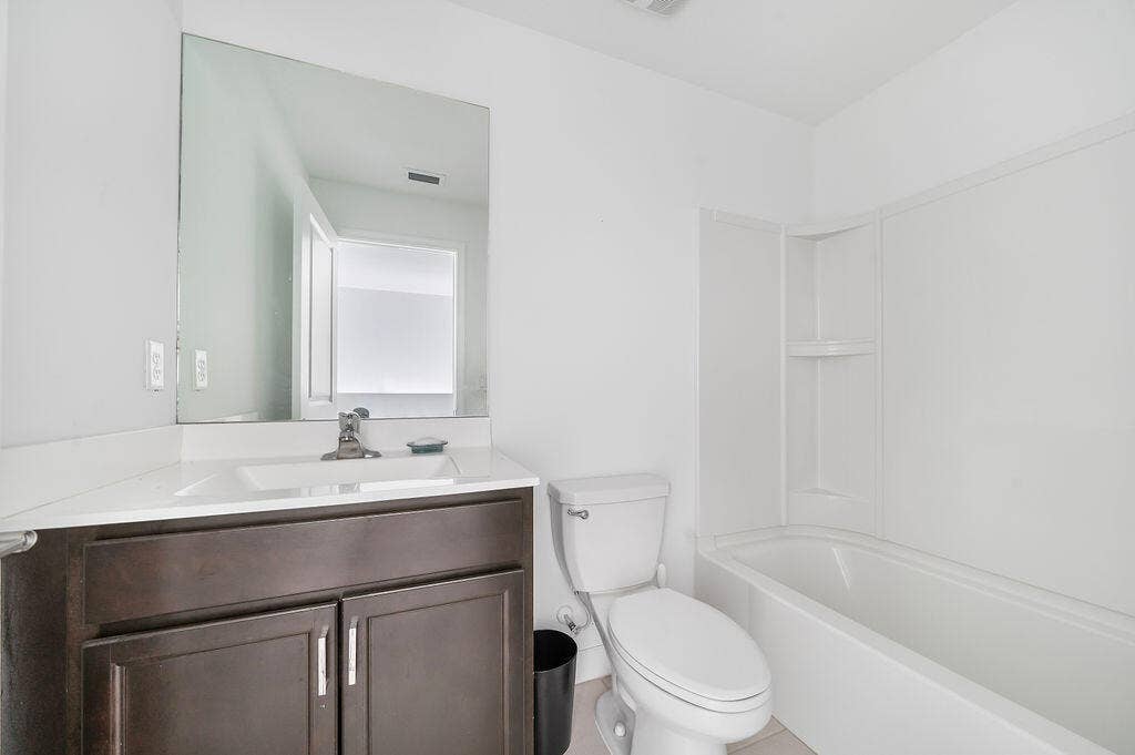 Bathroom with a dark wood-finish vanity, integrated sink, and a large wall-mounted mirror