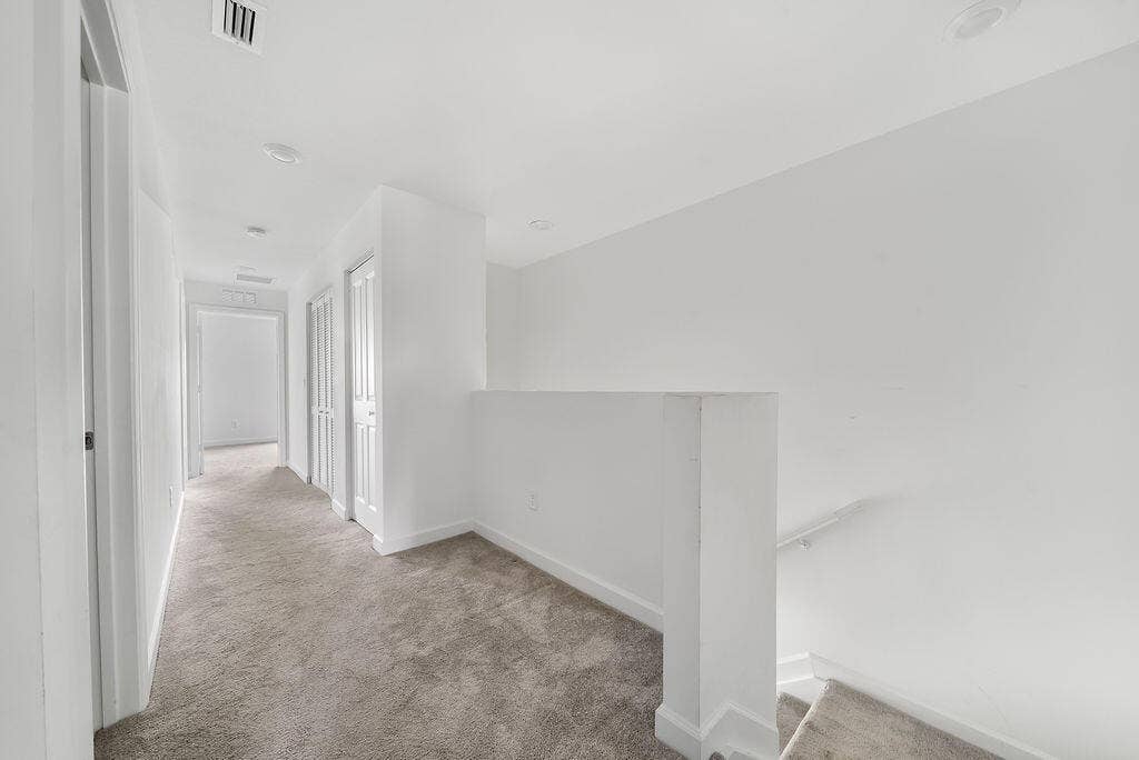 Upper-level hallway featuring neutral-toned carpeting, recessed lighting, and laundry closet