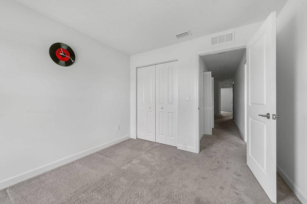Plush gray carpeting throughout, featuring white walls and baseboards