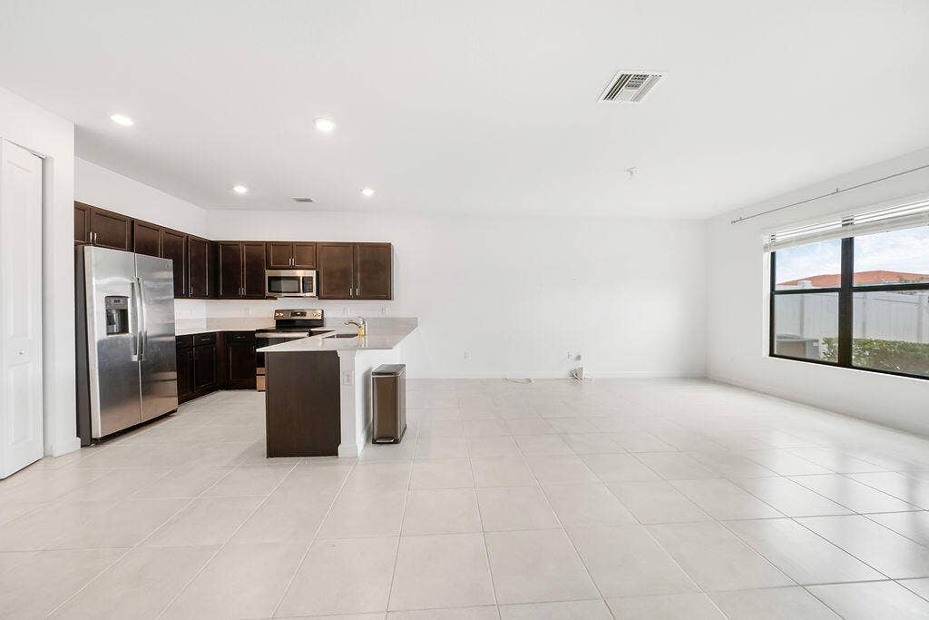 Open-concept living area featuring a kitchen with dark wood cabinetry, stainless steel appliances, and a snack bar