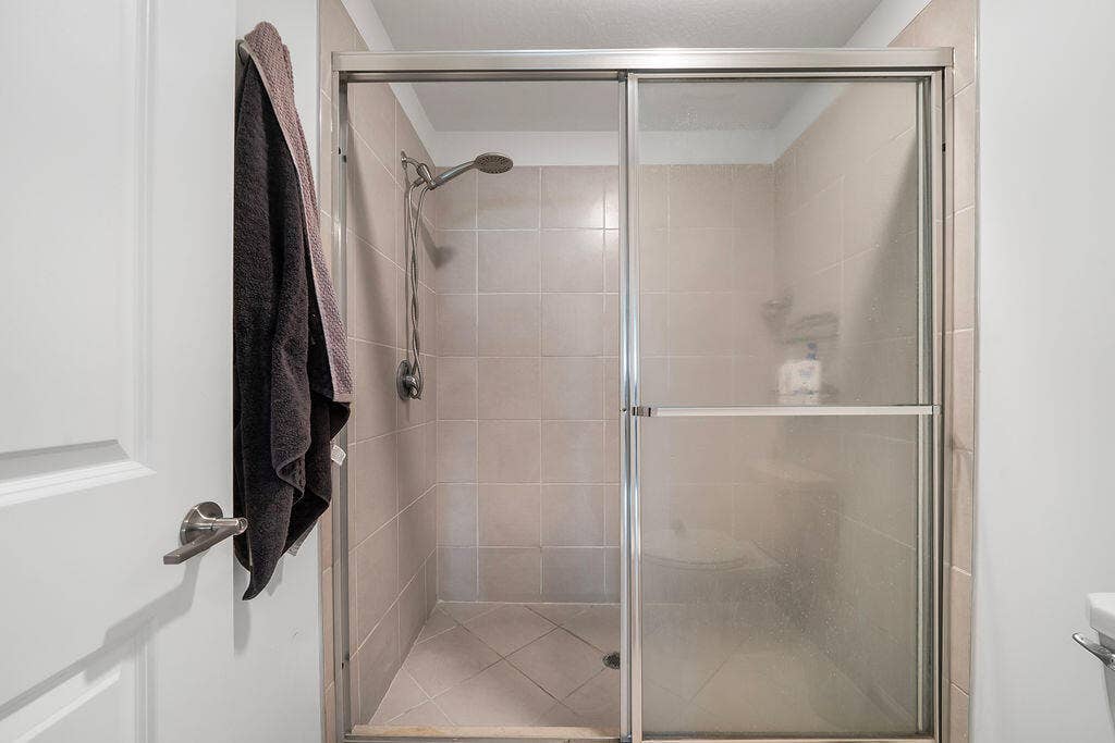 Enclosed shower with sliding glass doors and brushed nickel hardware