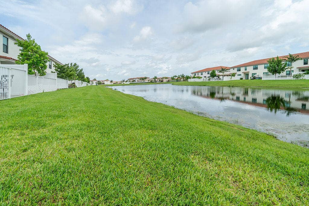Expansive green space with lake view featuring partially white privacy fenced yard