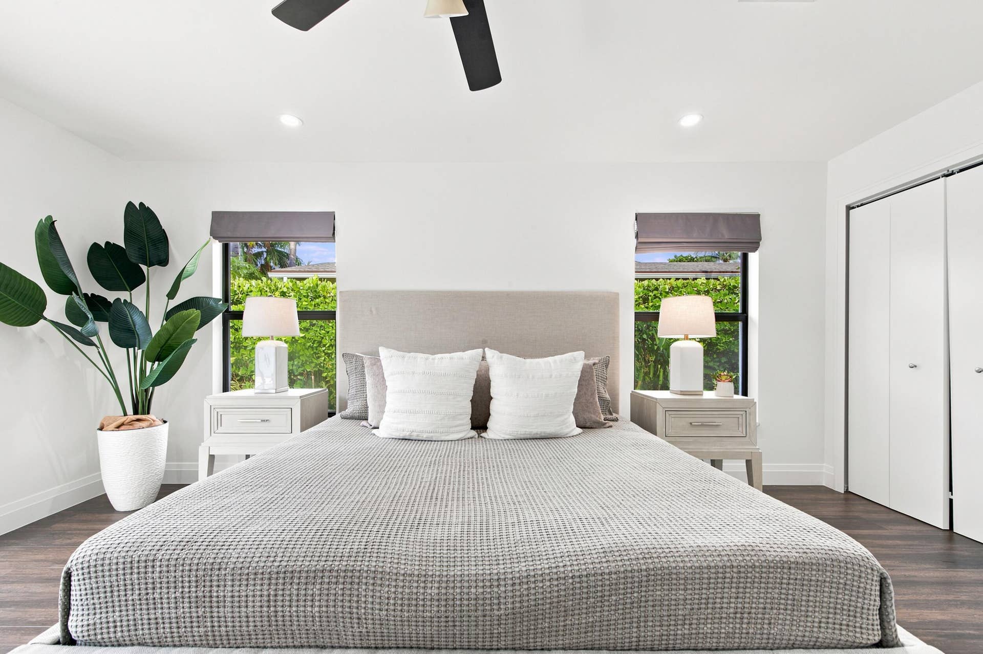 Bright bedroom featuring wood-finish flooring, two windows with window treatments, recessed lighting, and a ceiling fan