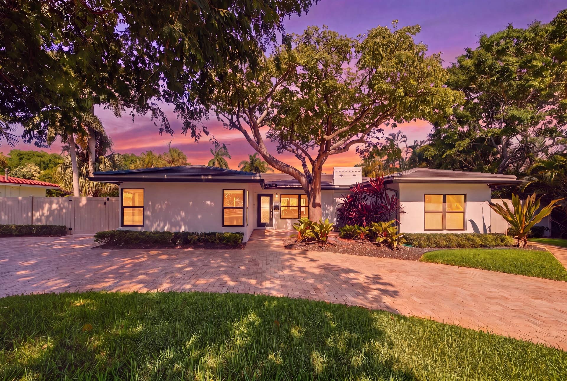 Contemporary residence featuring a paved driveway, mature trees, and landscaped grounds