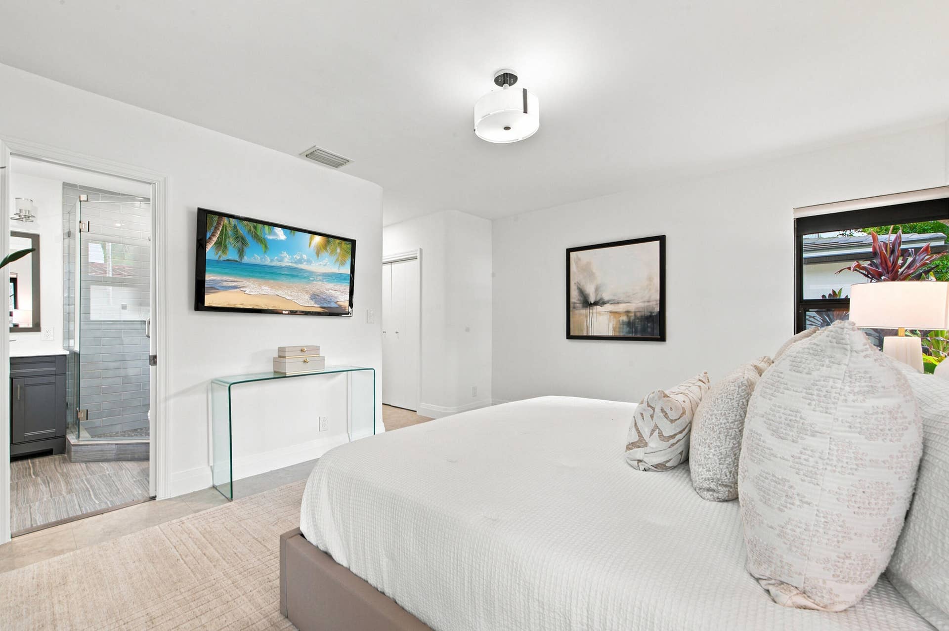 Bedroom featuring an en-suite bathroom with a glass-enclosed shower, a vanity with a dark wood-finish cabinet, and a large window providing natural light
