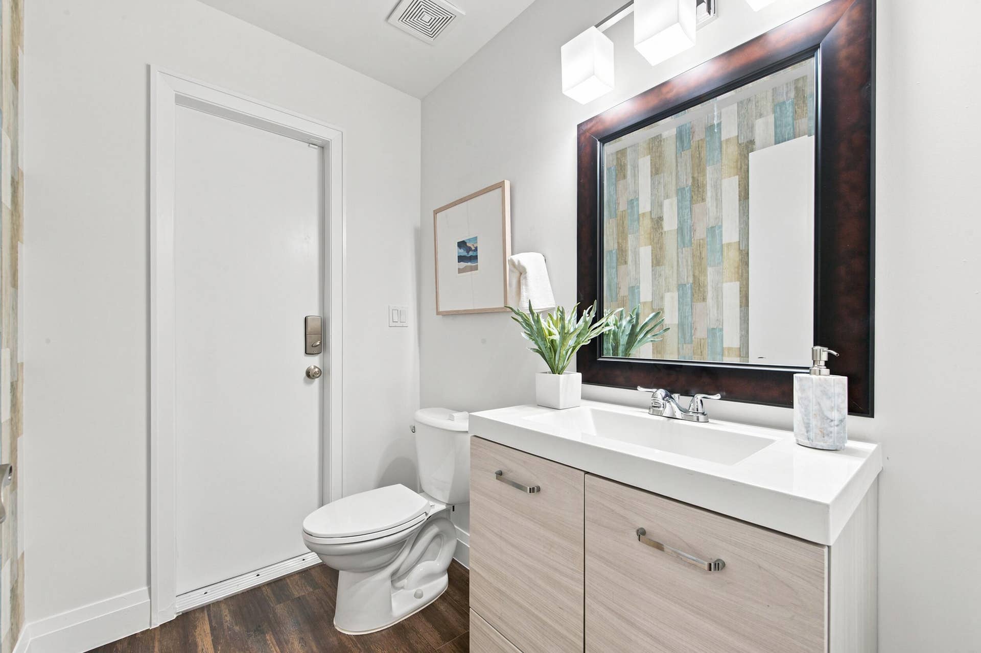 Bathroom featuring wood-finish flooring, a white toilet, and a vanity with a white countertop