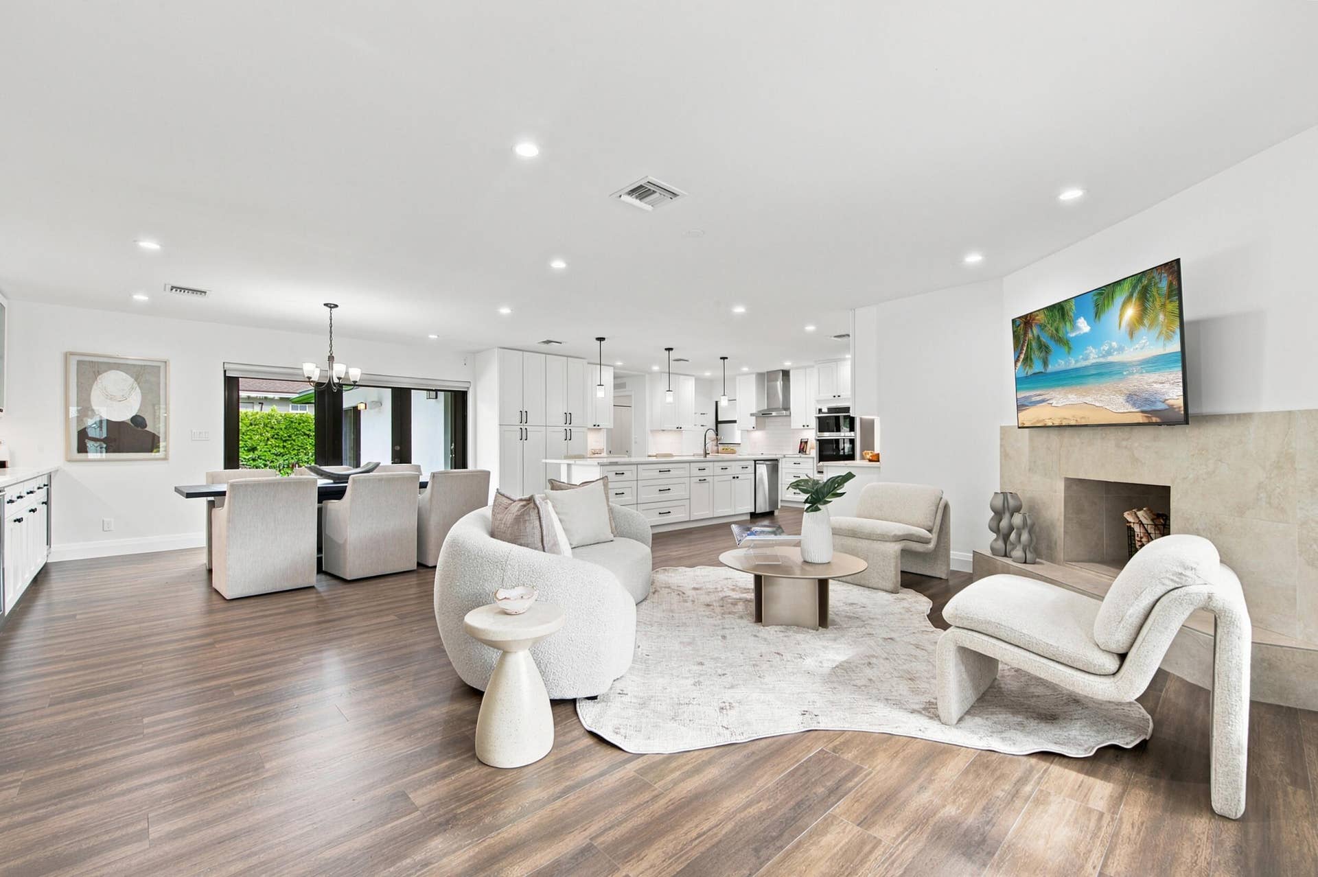 Open-concept living area featuring wood-finish flooring, recessed lighting, and a stone-clad fireplace