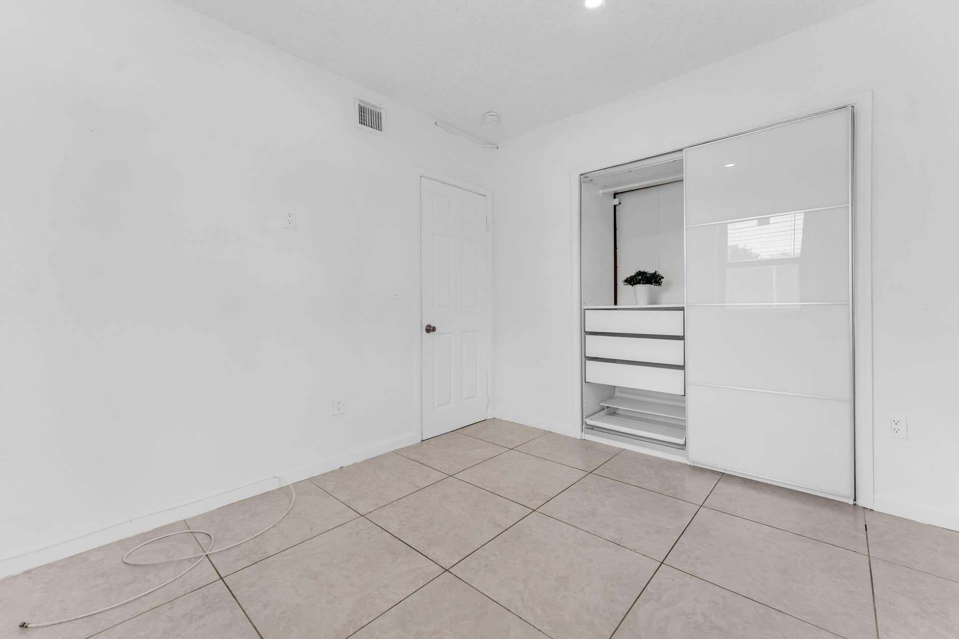 Recessed lighting illuminates a built-in closet with sliding doors, integrated drawers, and shelving