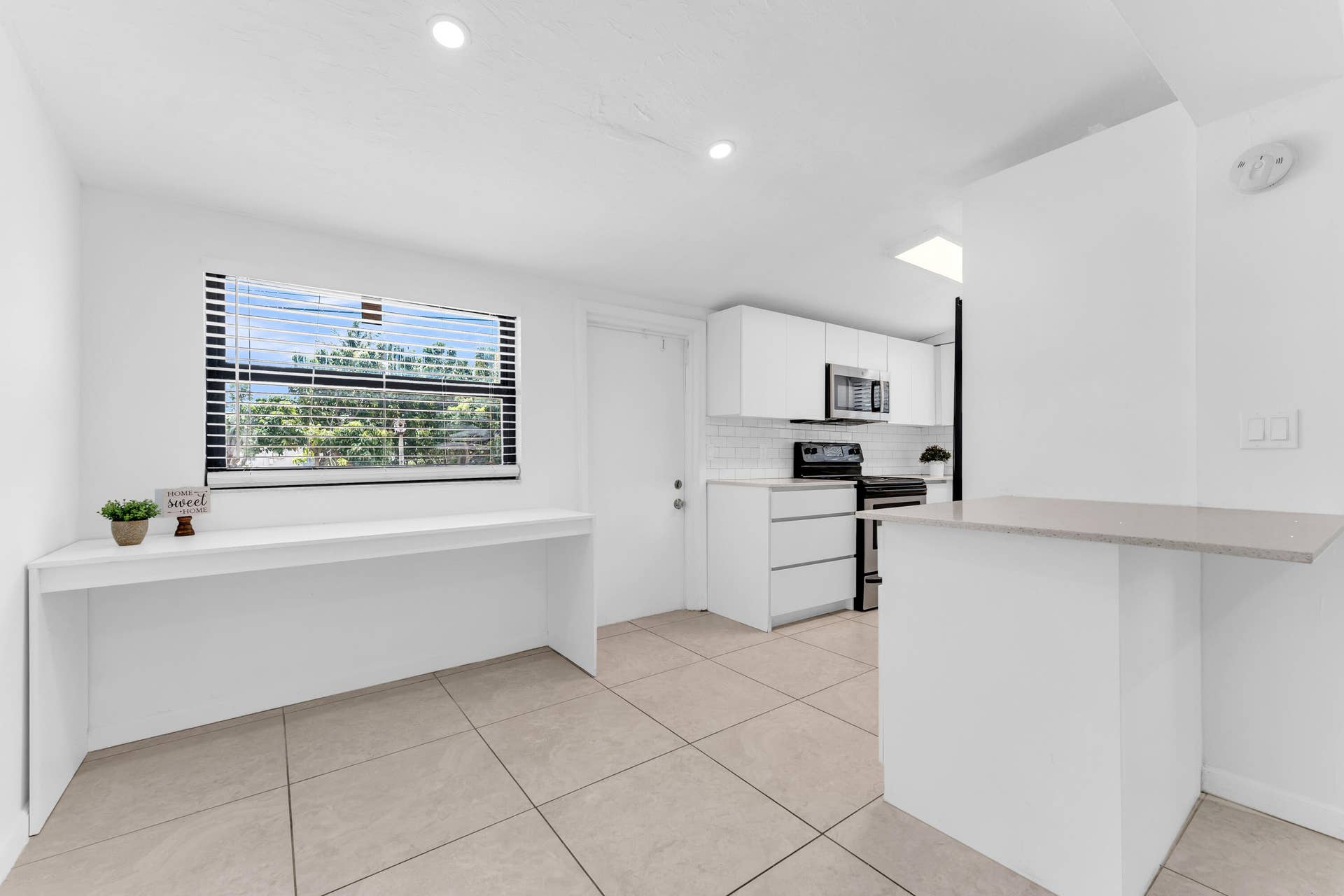 Kitchen area featuring a modern aesthetic with light-toned tiled flooring, white cabinetry, and stainless steel appliances