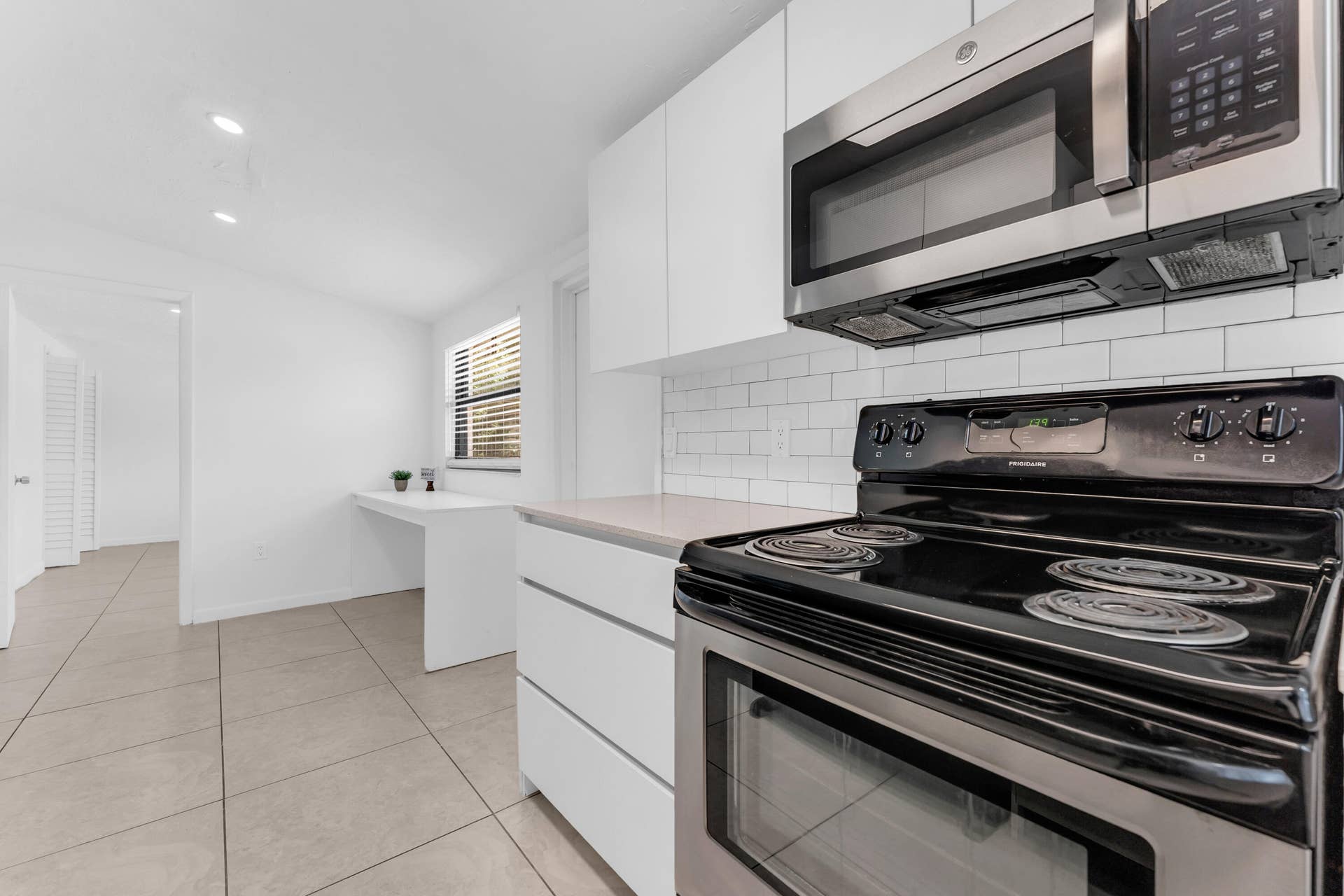 Kitchen featuring white flat-panel cabinetry, light-toned countertops, and a white subway tile backsplash