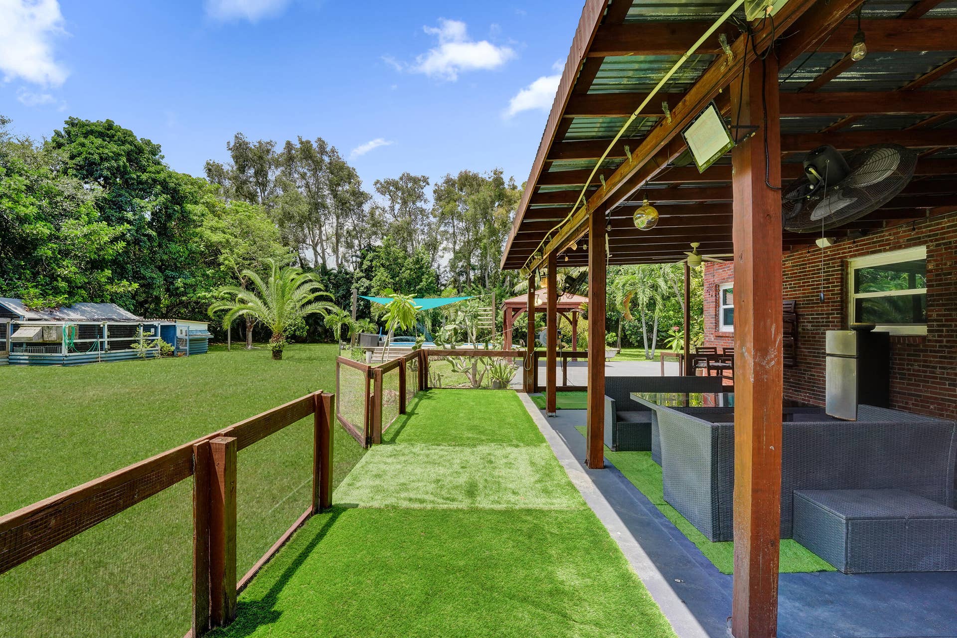 Covered side patio with turf is a convenient additional fenced area- perfect for kids and pets!!