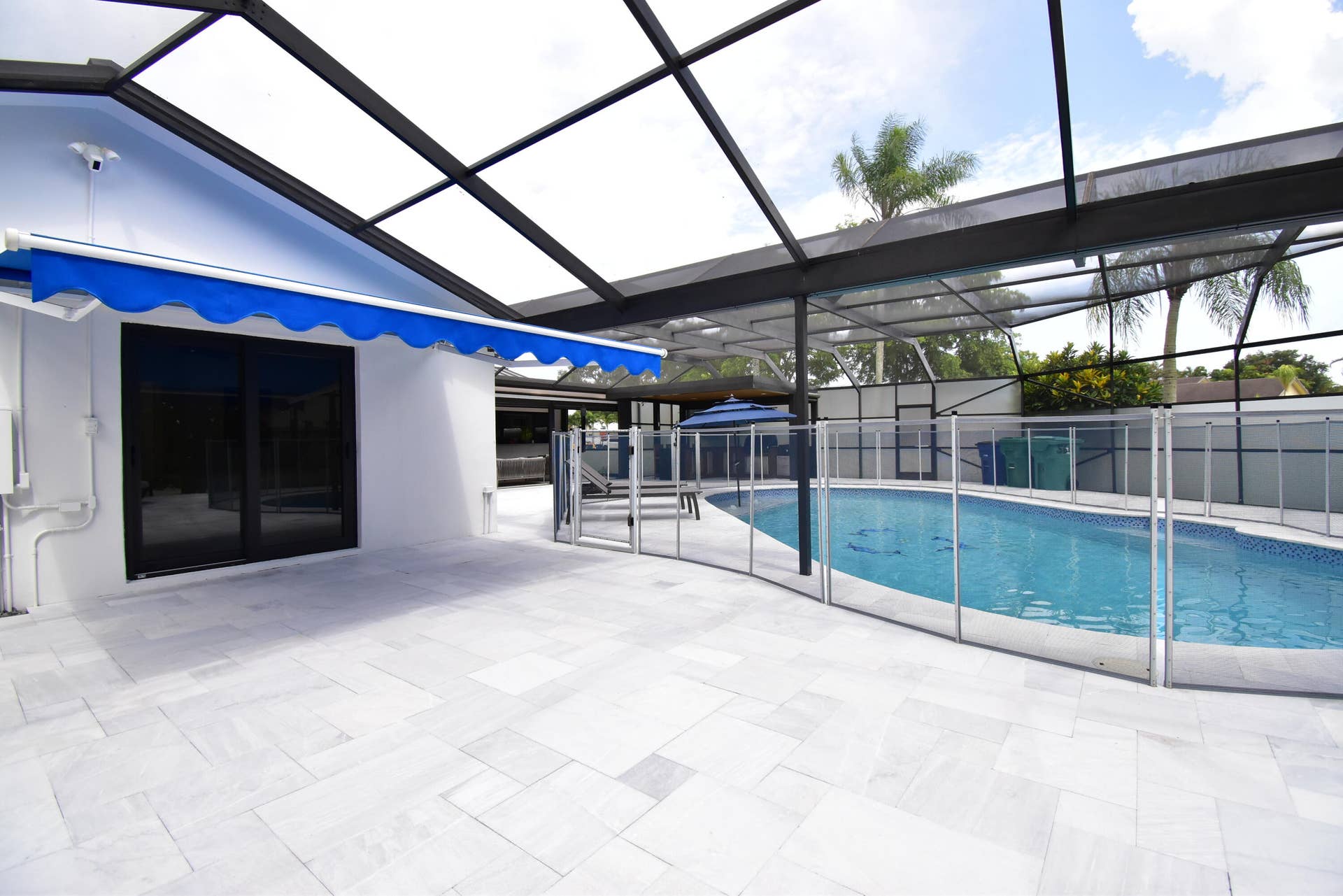 5061 SW 87TH Terrace, Cooper City, FL 33328 Screened-in pool area featuring a rectangular swimming pool with a mosaic tile interior, a safety fence, and an expansive light-toned paver deck