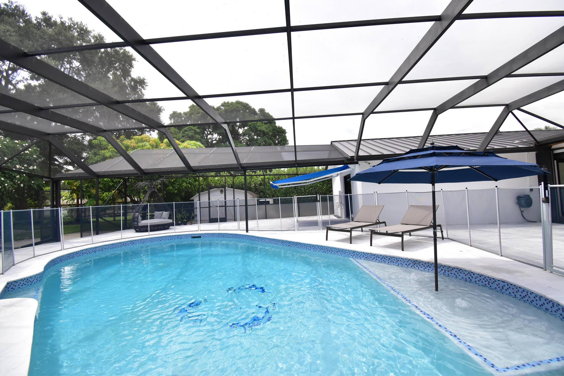 5061 SW 87TH Terrace, Cooper City, FL 33328 Screened-in pool area featuring a curved swimming pool with decorative tile accents and an integrated spa