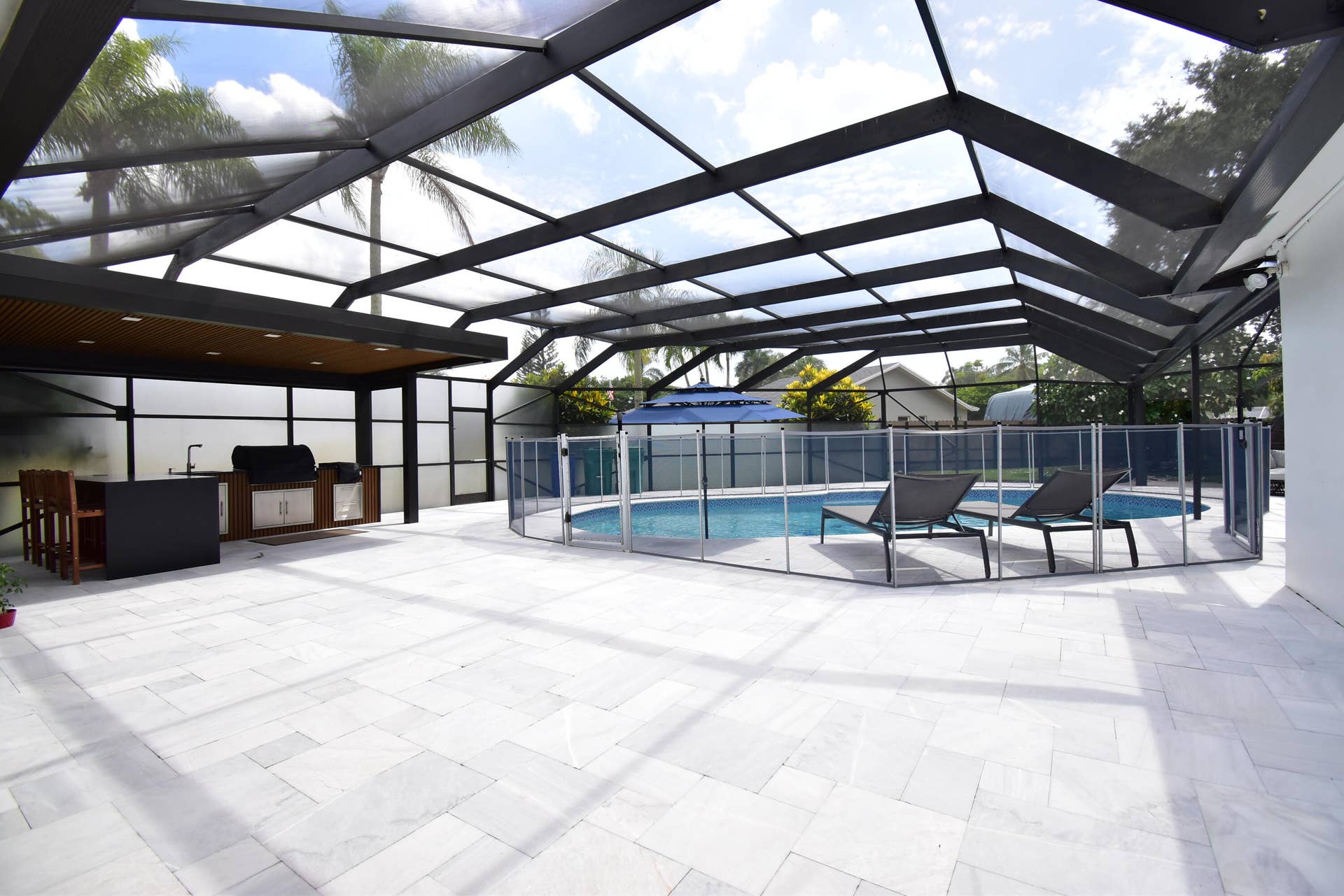 5061 SW 87TH Terrace, Cooper City, FL 33328 Expansive screened patio featuring light-toned paver flooring, a built-in outdoor kitchen with a sink and grill, and a fenced swimming pool