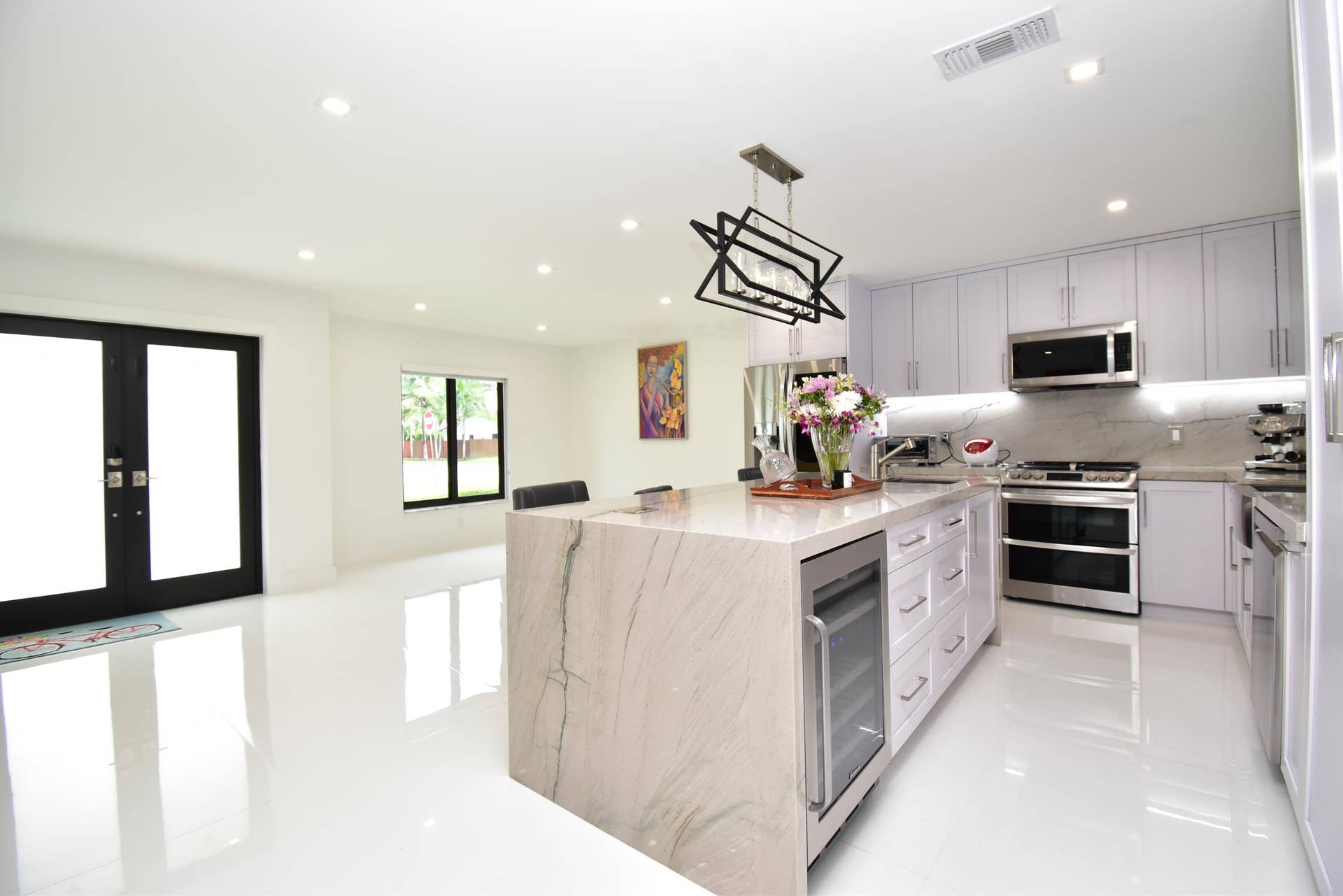 5061 SW 87TH Terrace, Cooper City, FL 33328 Modern kitchen featuring a waterfall island with integrated wine refrigerator, stainless steel appliances, light cabinetry, recessed lighting, and white tile flooring