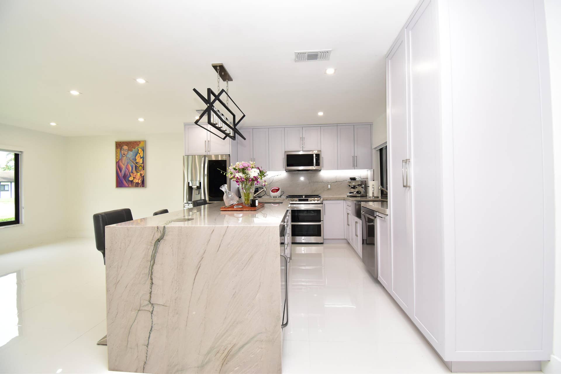 5061 SW 87TH Terrace, Cooper City, FL 33328 Modern kitchen featuring a waterfall island, stainless steel appliances, white cabinetry, recessed lighting, and a linear chandelier