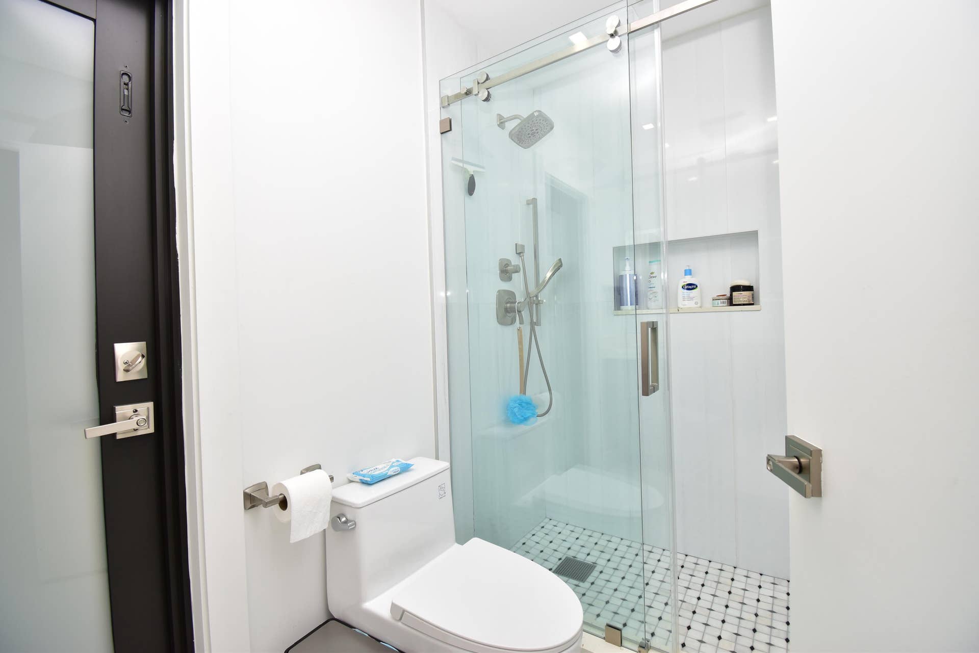 5061 SW 87TH Terrace, Cooper City, FL 33328 Bathroom featuring a glass-enclosed shower with sliding door, wall-mounted shower system, and recessed shelving