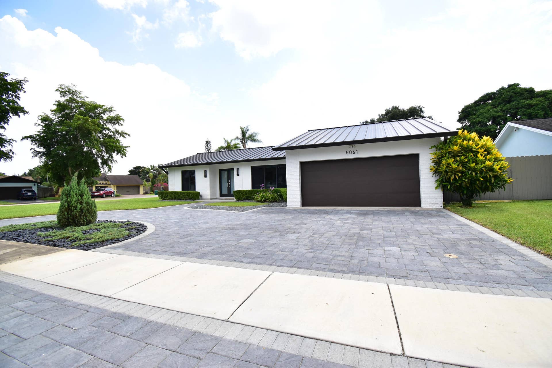 5061 SW 87TH Terrace, Cooper City, FL 33328 White brick facade with dark trim accents and a black metal roof