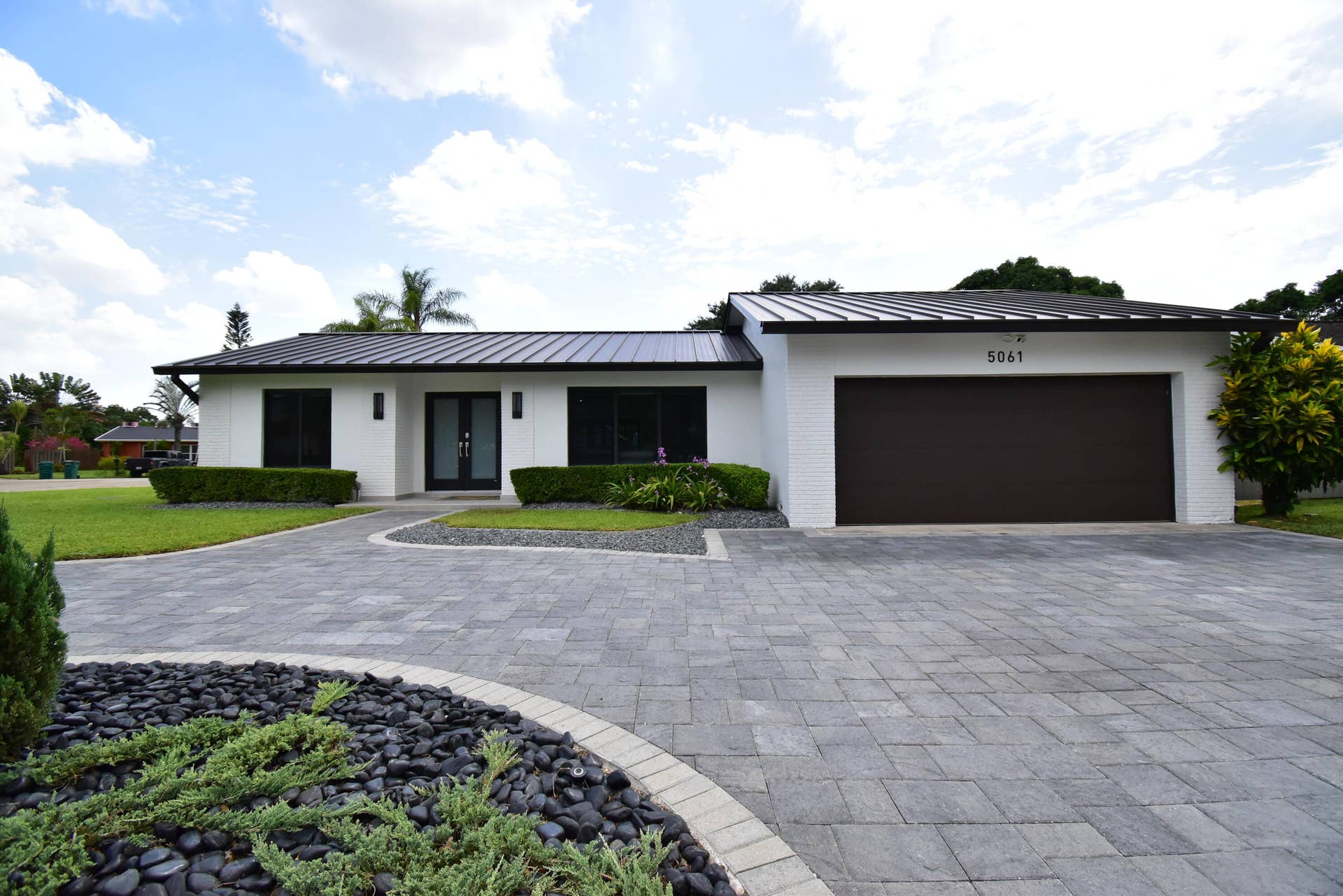 5061 SW 87TH Terrace, Cooper City, FL 33328 Contemporary residence featuring a crisp white facade and a dark metal roof