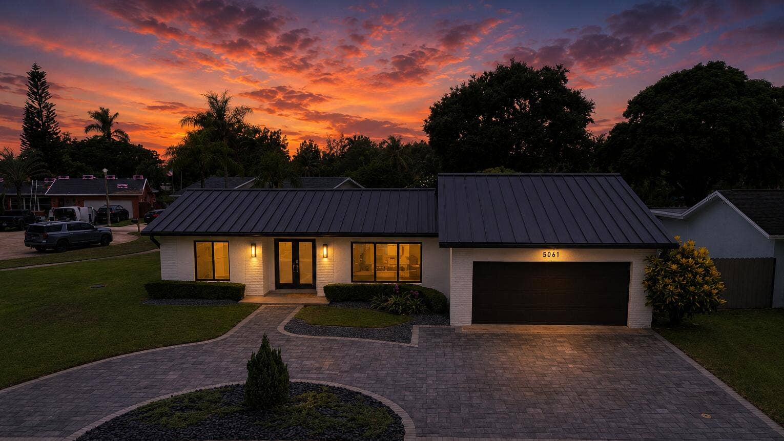 5061 SW 87TH Terrace, Cooper City, FL 33328 Contemporary exterior featuring a dark standing seam metal roof, white painted brick facade, a two-car garage, and a paver driveway