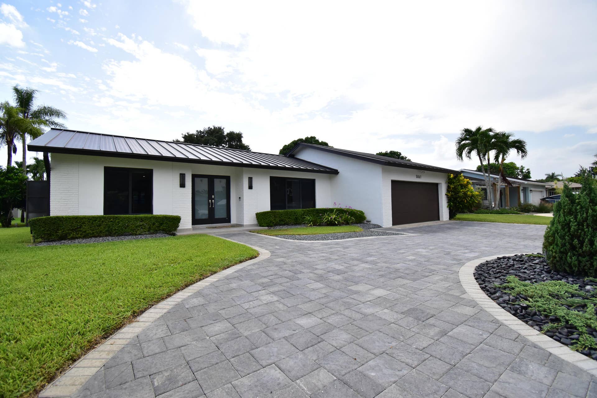5061 SW 87TH Terrace, Cooper City, FL 33328 Contemporary residence featuring a black metal roof, white exterior siding, and a paver driveway