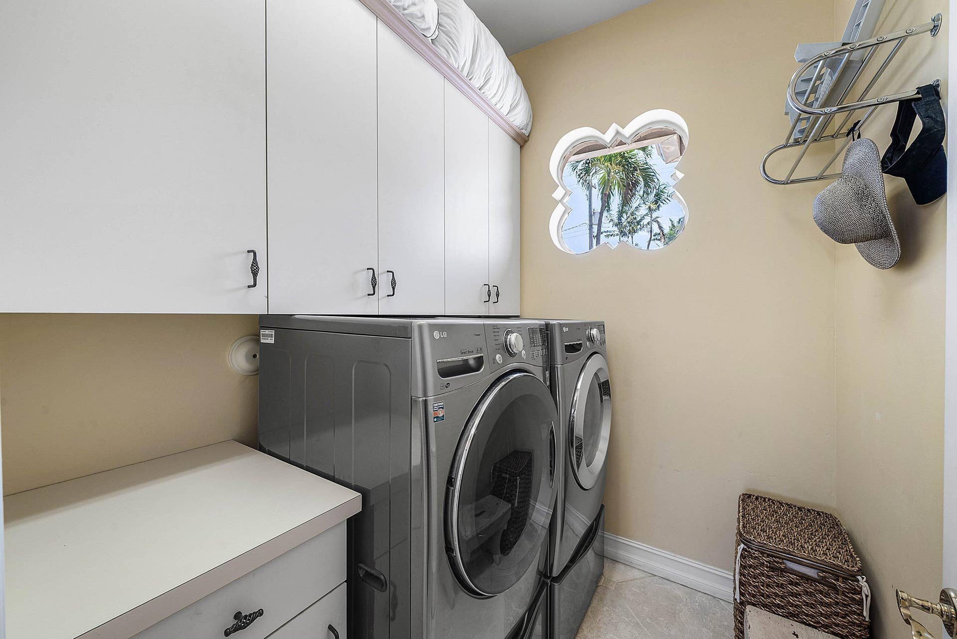 2761 NE 48TH Court, Lighthouse Point, FL 33064 Dedicated laundry room featuring white cabinetry, a decorative window, and light-colored flooring