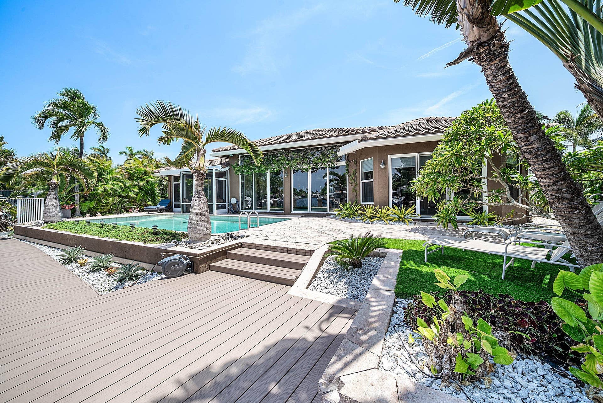 2761 NE 48TH Court, Lighthouse Point, FL 33064 Expansive outdoor living area featuring a swimming pool, composite decking, and mature tropical landscaping