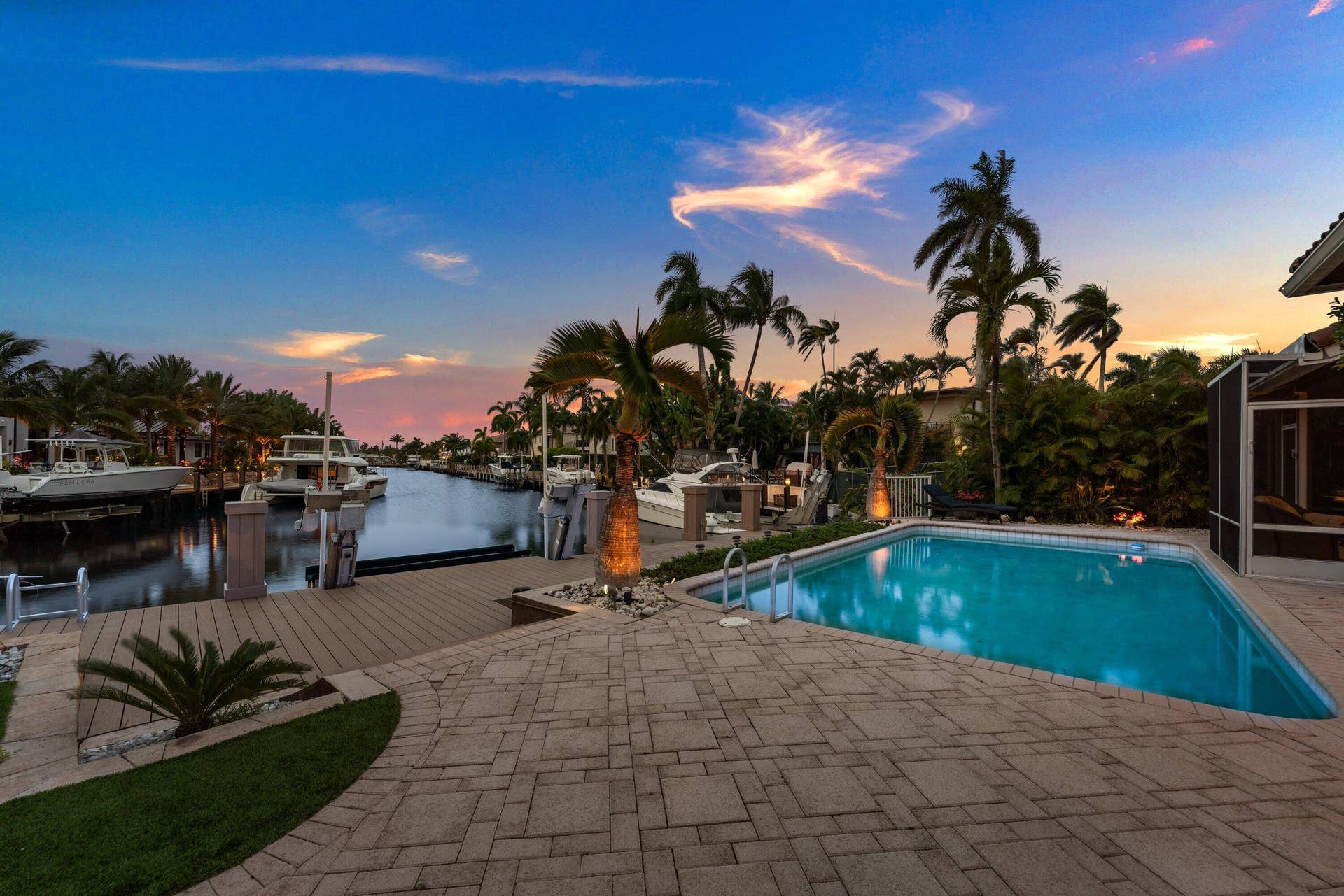 2761 NE 48TH Court, Lighthouse Point, FL 33064 Waterfront property featuring a rectangular pool, paver patio, composite decking, and mature palm trees