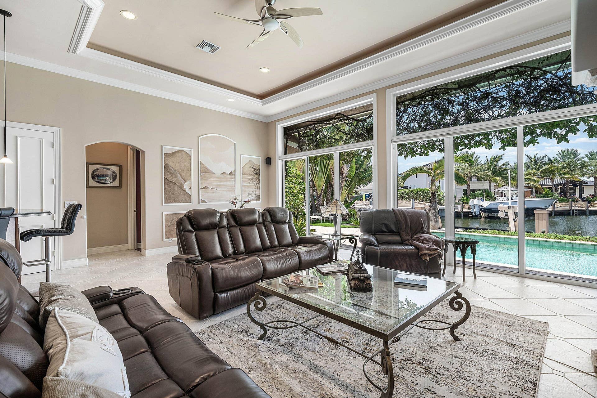 2761 NE 48TH Court, Lighthouse Point, FL 33064 Spacious living area featuring floor-to-ceiling sliding glass doors, tray ceiling with recessed lighting, tile flooring, and a ceiling fan