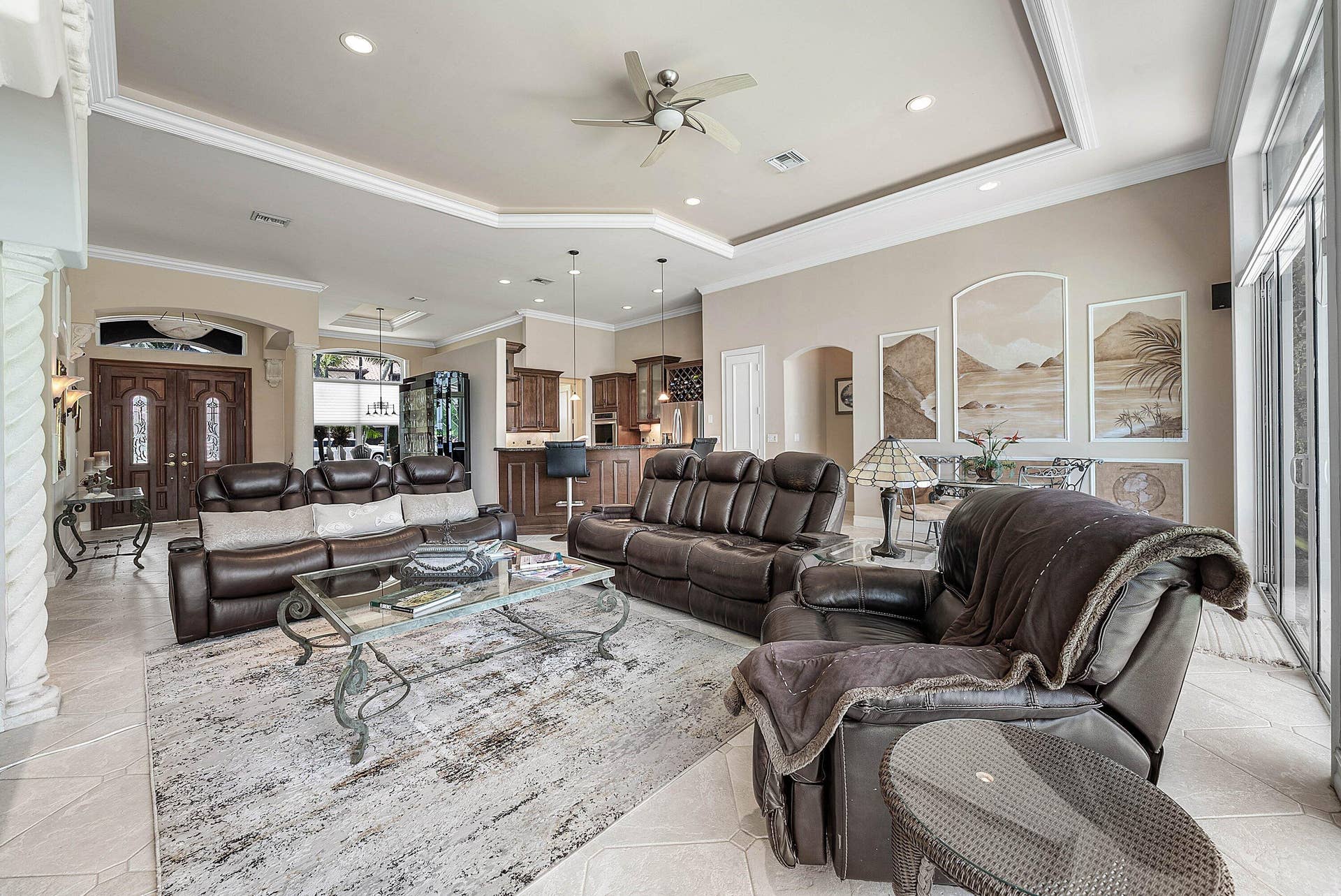 2761 NE 48TH Court, Lighthouse Point, FL 33064 Expansive living area featuring light-toned tile flooring, tray ceilings with recessed lighting and a ceiling fan, and large sliding glass doors