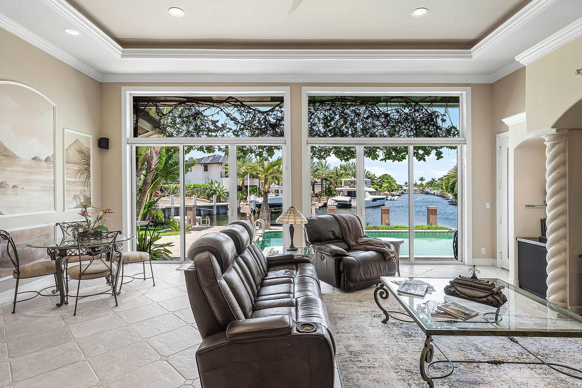 2761 NE 48TH Court, Lighthouse Point, FL 33064 Living area featuring extensive window walls, recessed lighting, tray ceiling, tile flooring, and direct water frontage with a pool
