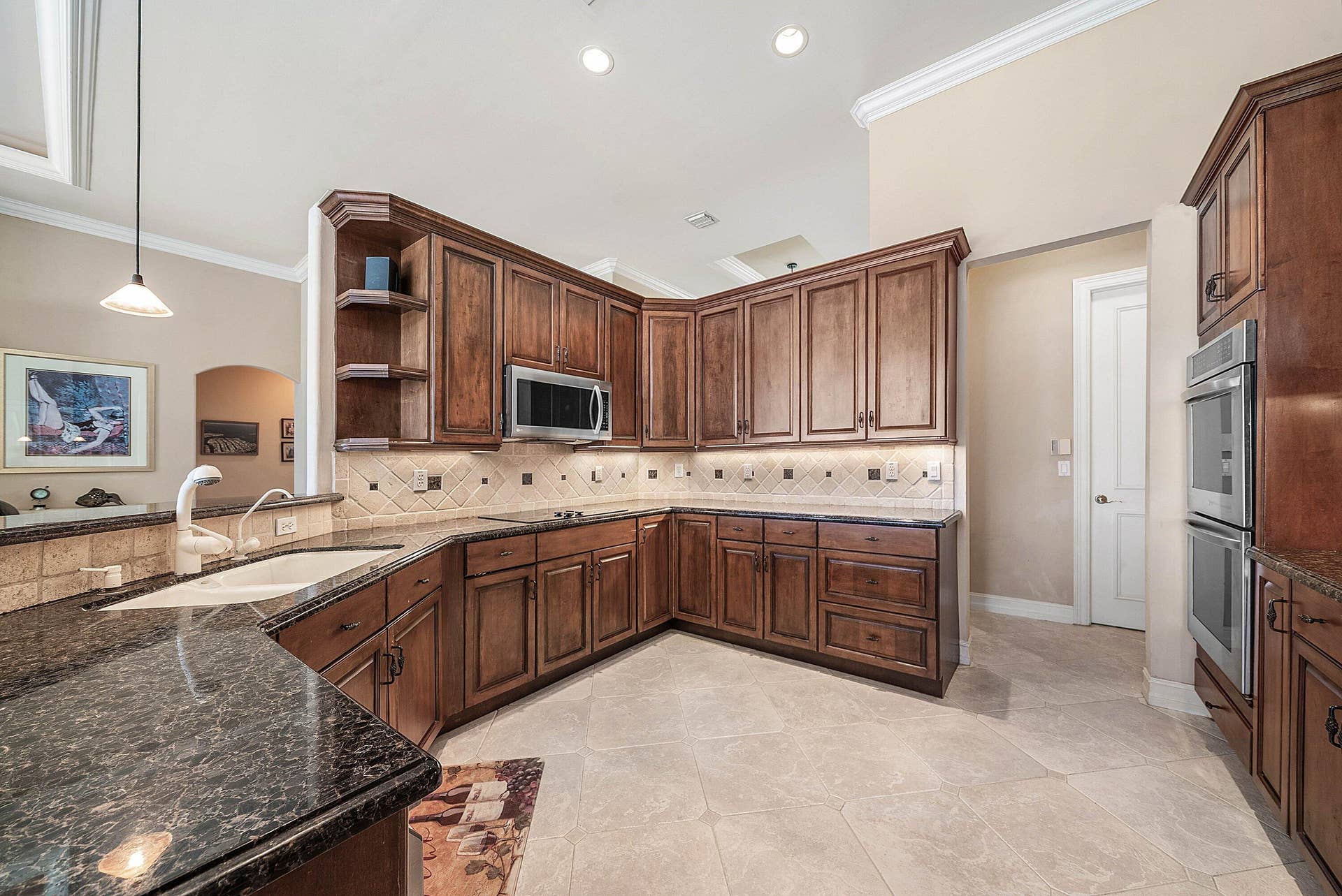 2761 NE 48TH Court, Lighthouse Point, FL 33064 Kitchen featuring rich wood cabinetry, dark speckled countertops, and a tiled backsplash