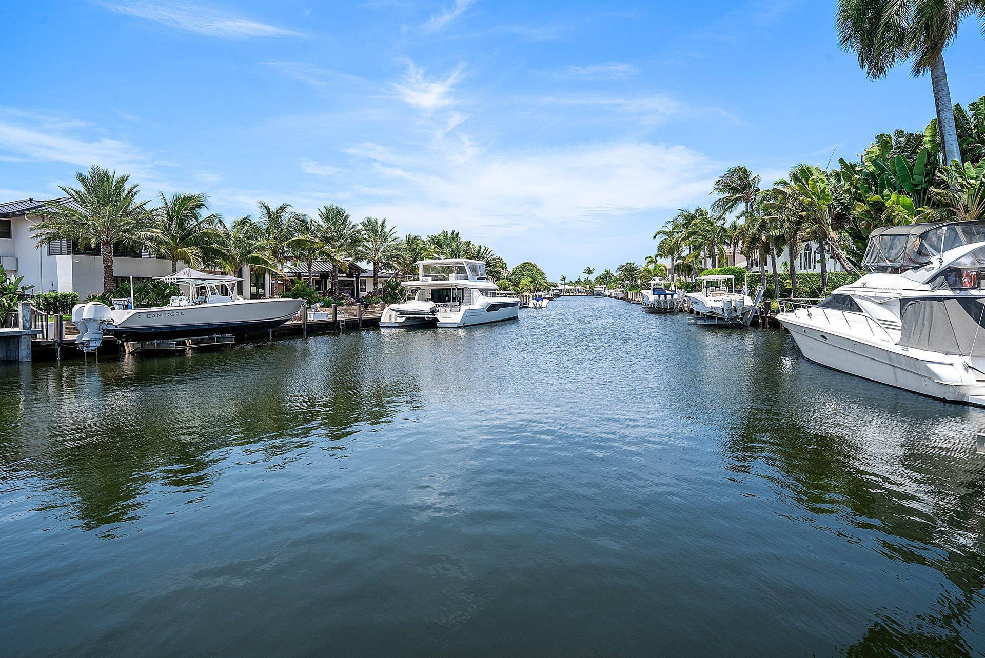 2761 NE 48TH Court, Lighthouse Point, FL 33064 Waterfront property featuring a private boat dock, lush tropical landscaping, and mature palm trees