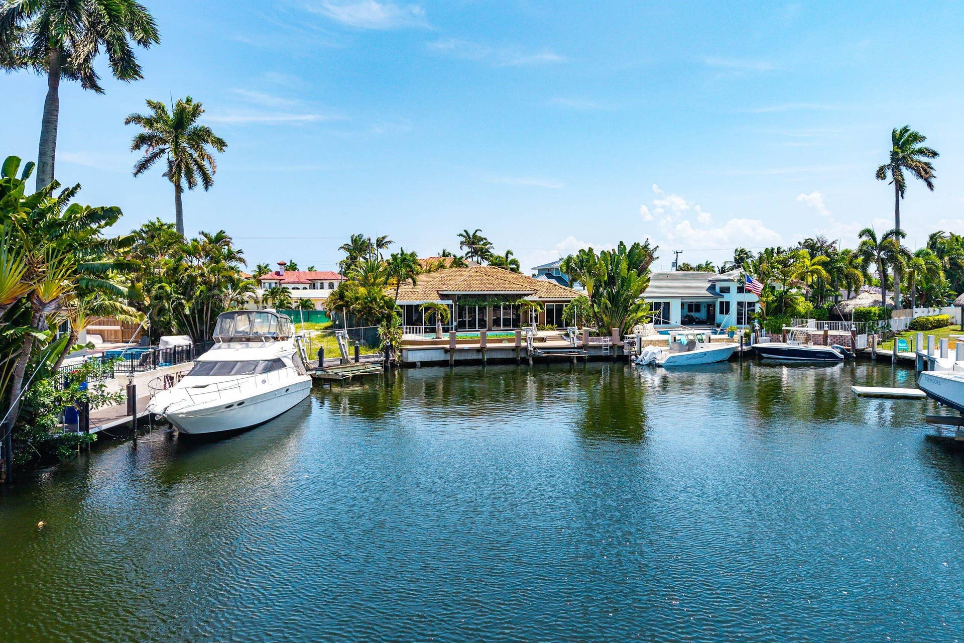 2761 NE 48TH Court, Lighthouse Point, FL 33064 Waterfront property featuring a private boat dock, mature palm trees, and lush tropical landscaping