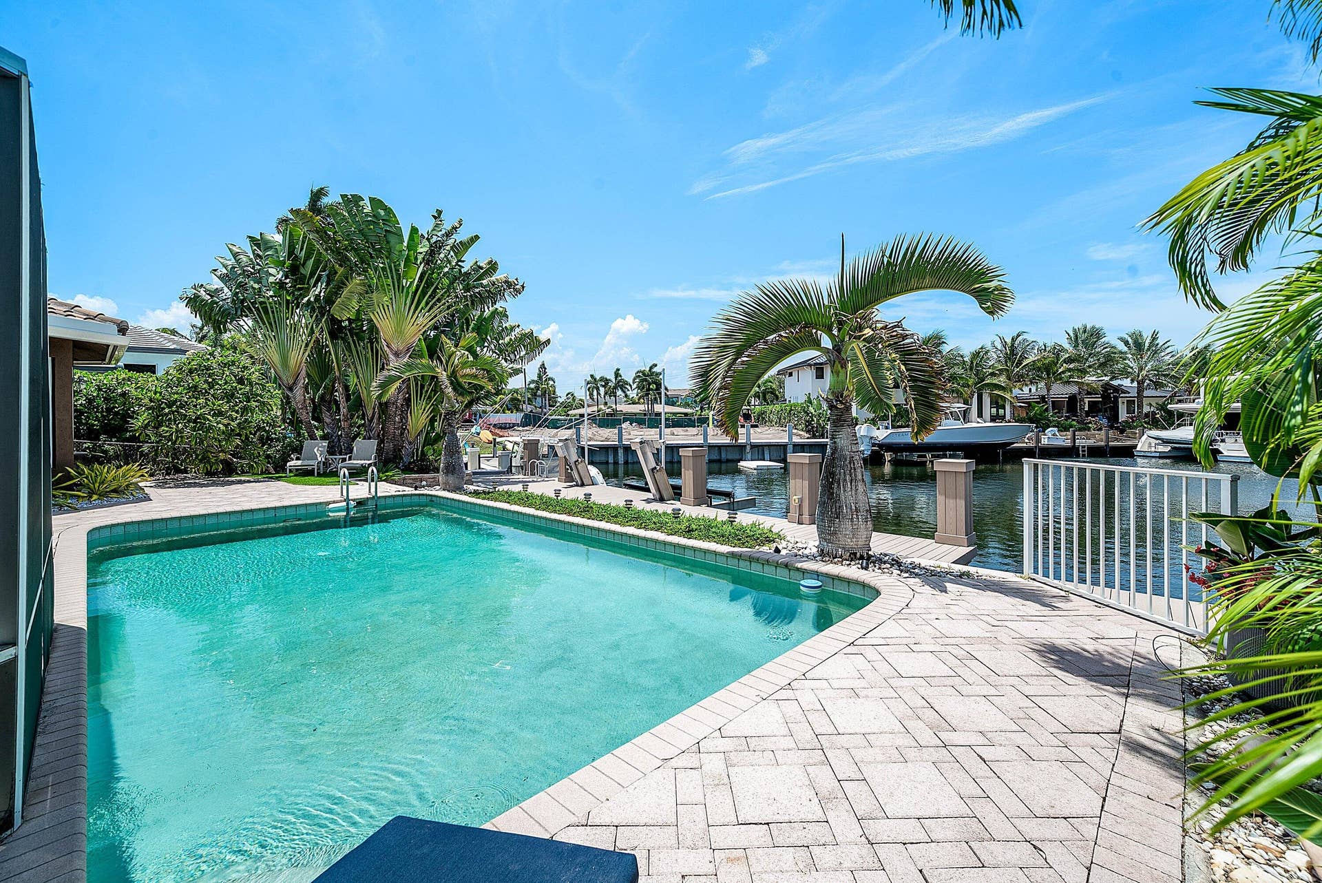 2761 NE 48TH Court, Lighthouse Point, FL 33064 Waterfront property featuring a private swimming pool with integrated steps, a paver patio, lush tropical landscaping, and a private dock