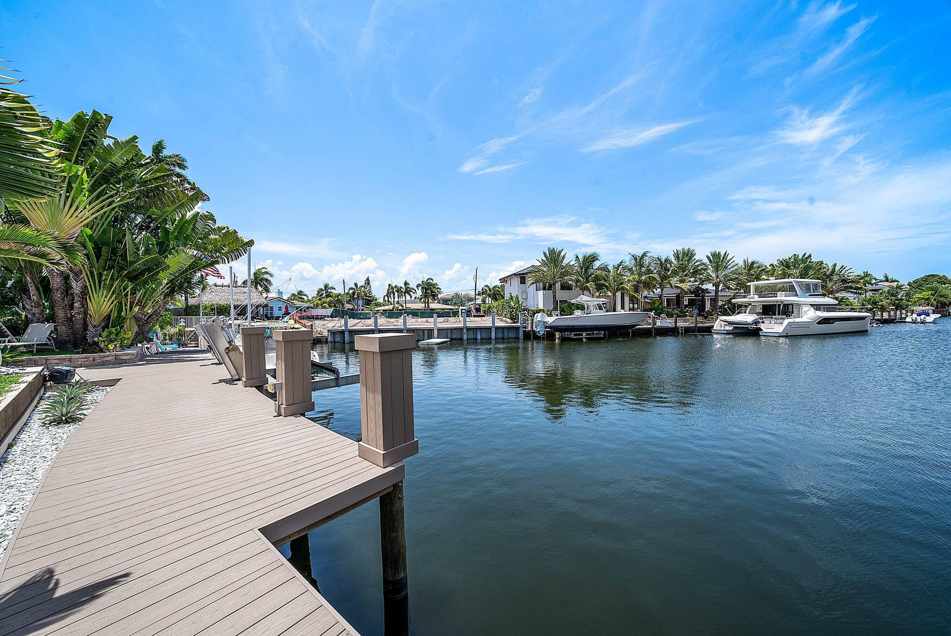 2761 NE 48TH Court, Lighthouse Point, FL 33064 Waterfront property featuring a composite dock, boat lift, and mature tropical landscaping